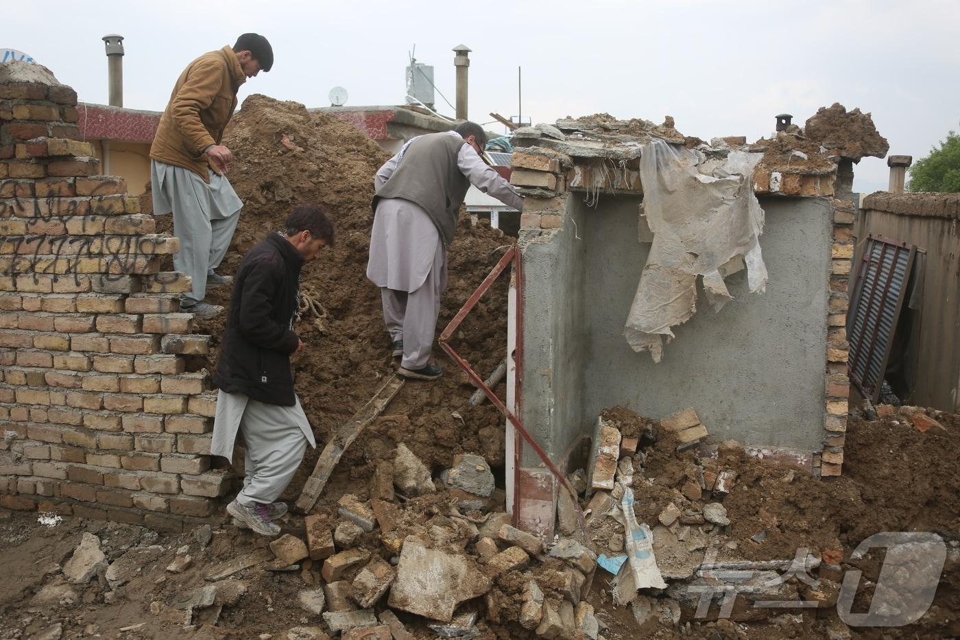 본문 이미지 - 아프가니스탄 시민들이 5일(현지시간) 수도 카불에서 폭우로 무너진 집을 확인하고 있다. 2026.4.5 ⓒ 신화=뉴스1