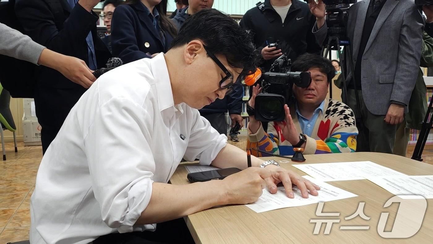 본문 이미지 - 한동훈 전 국민의힘 대표가 14일 부산 북구 만덕2동 주민센터에서 전입신고서에 서명하고 있다. (한 전 대표측 제공. 재판매 및 DB 금지) 2026.4.14 ⓒ 뉴스1