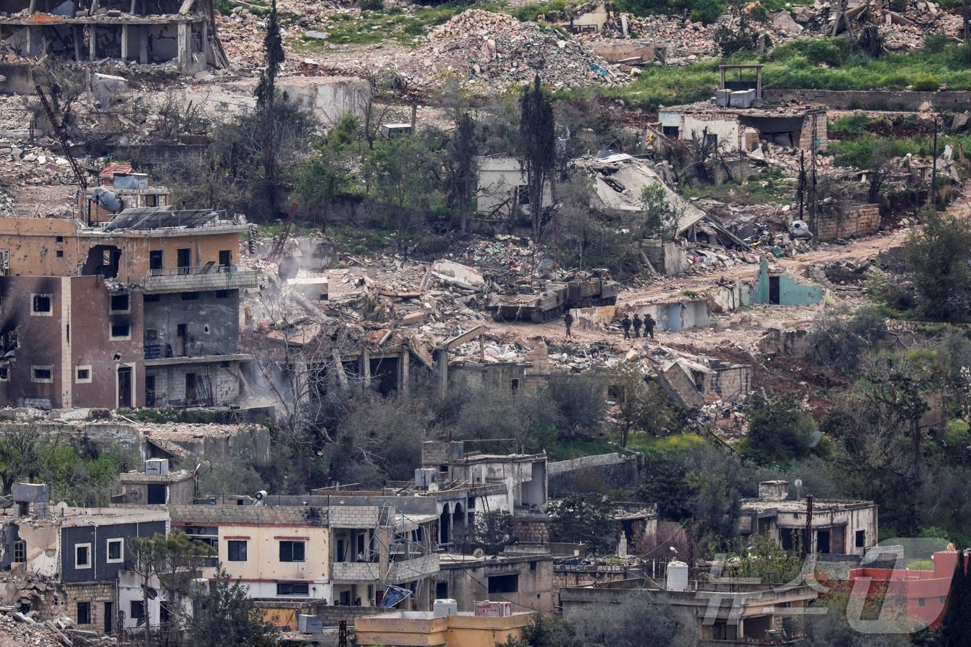 본문 이미지 - 이스라엘군 병력이 14일(현지시간) 국경 인근 남부 레바논 지역에서 공습으로 파괴된 건물들 사이를 지나가고 있다. 2026.04.15. ⓒ 로이터=뉴스1