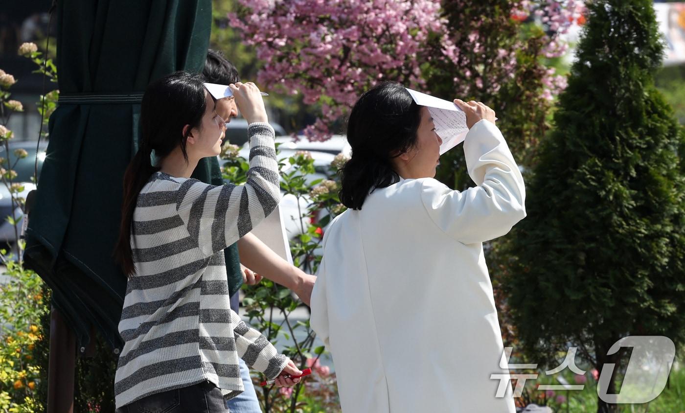 본문 이미지 - 낮 최고기온이 26도까지 오르는 등 초여름 같은 날씨를 보인 15일 오후 서울 중구 시청역 인근에서 시민들이 종이로 햇빛을 가리며 이동하고 있다. 2026.4.15 ⓒ 뉴스1 임지훈 인턴기자