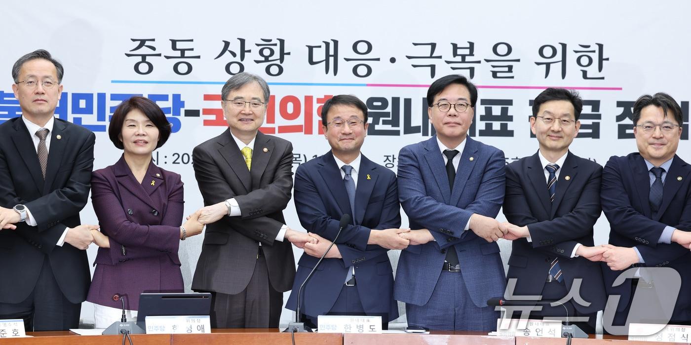 본문 이미지 - 한병도 더불어민주당 원내대표와 송언석 국민의힘 원내대표가 16일 서울 여의도 국회에서 열린 중동 상황 대응·극복을 위한 더불어민주당-국민의힘 원내대표 긴급 점검 회의에서 기념 촬영을 위해 손을 맞잡고 있다. 왼쪽부터 이형일 재정경제부 1차관, 한정애 더불어민주당 정책위의장, 조현 외교부 장관, 한 원내대표, 송 원내대표, 윤창렬 국무조정실장. ⓒ 뉴스1 신웅수 기자