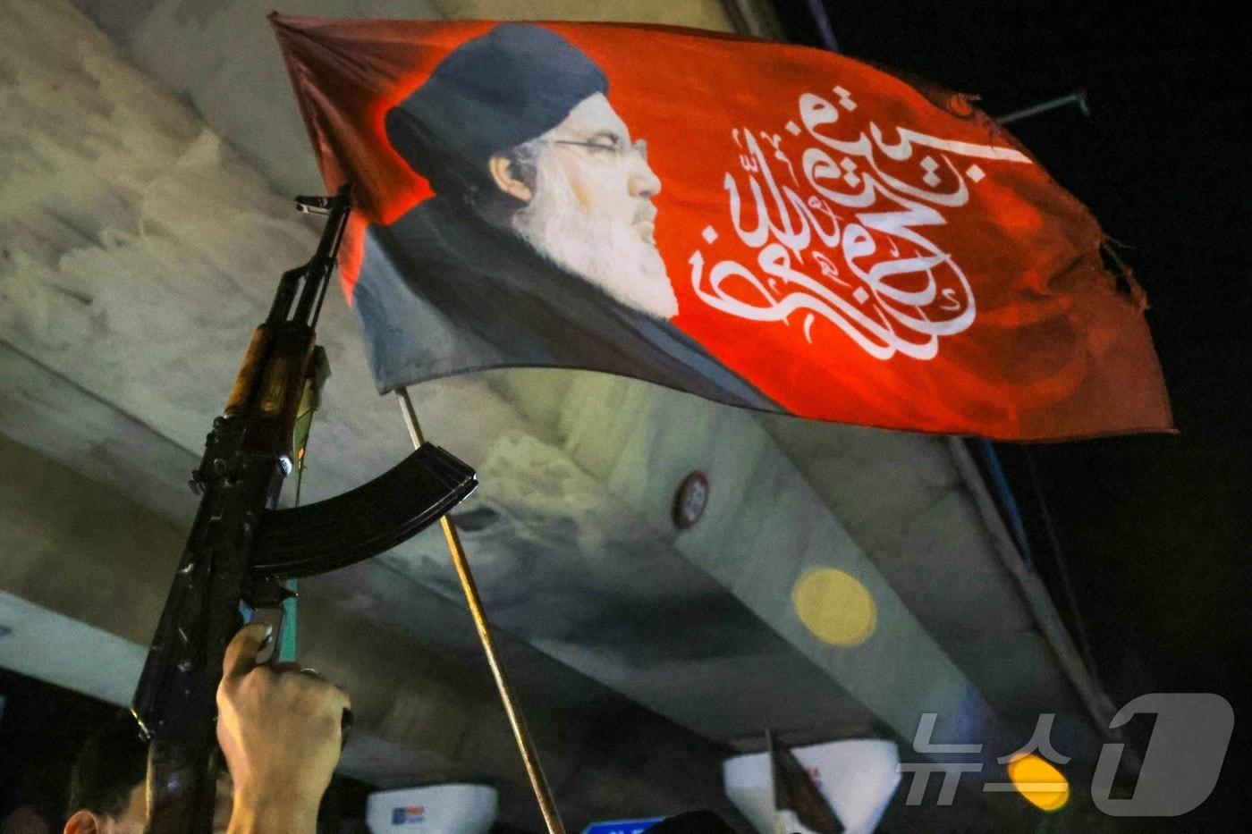 본문 이미지 - 헤즈볼라 지지자가 17일(현지시간) 레바논 베이루트 남부 교외에서 이스라엘과 레바논간 휴전이 발효되자 기관총을 들고 축하하고 있다. 2026.4.17 ⓒ AFP=뉴스1