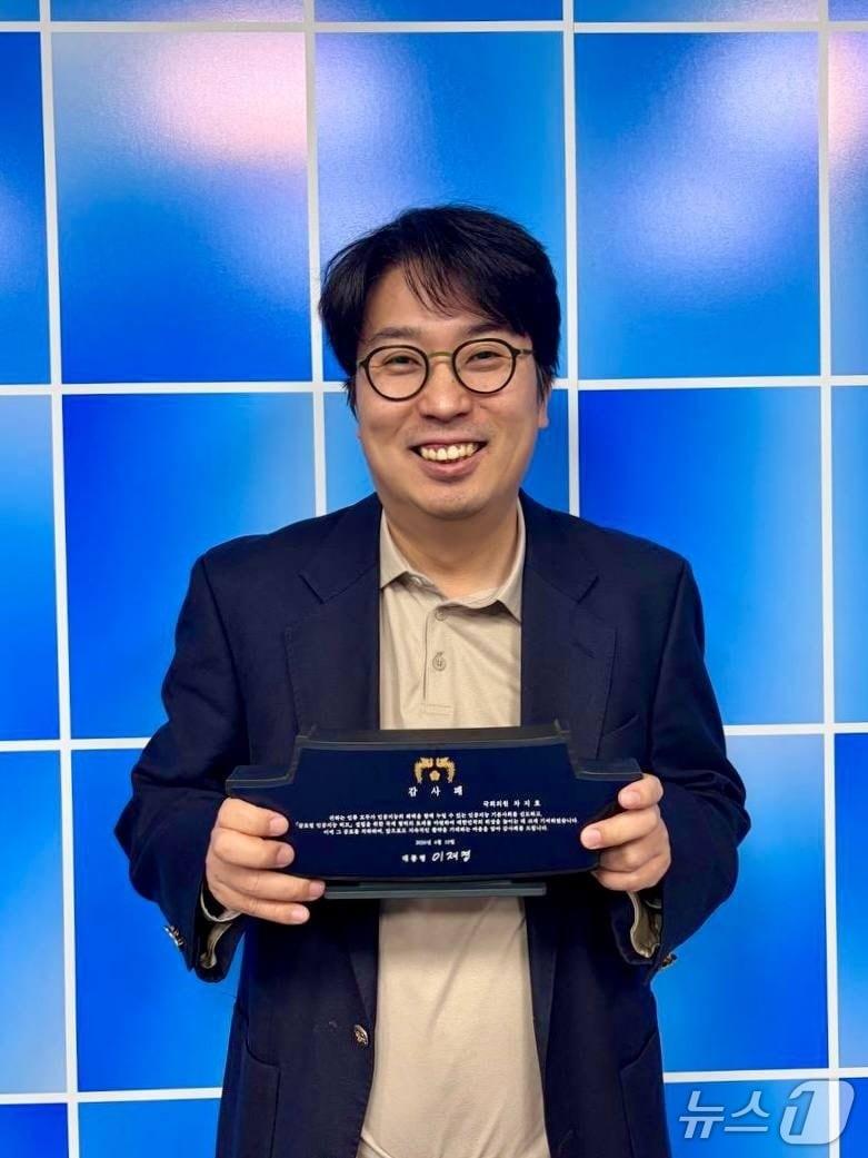 본문 이미지 - 이재명 대통령은 지난 10일 AI 기본사회 정책 설계를 주도한 공로로 차지호 더불어민주당 의원에게 감사패를 수여했다. 차 의원이 감사패를 들고 있는 모습.(청와대 제공). 2026. 4. 18/뉴스1