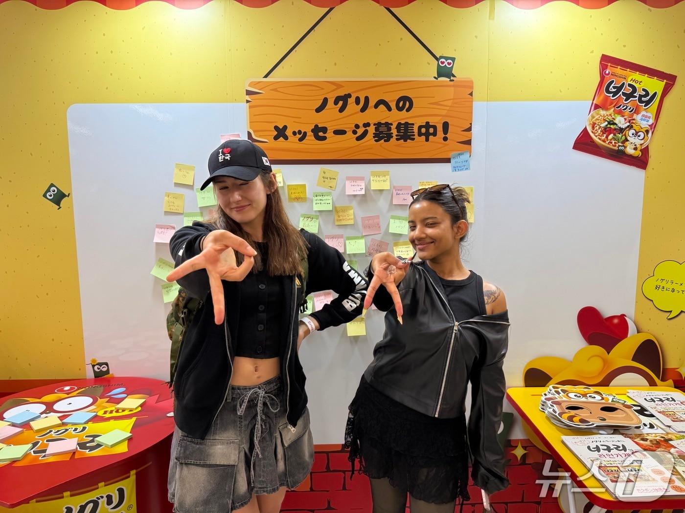 본문 이미지 - 16일 도쿄에서 열린 '2026 코리아 엑스포'를 찾은 브라질인 실비아 사 씨가 방글라데시인 친구와 함께 너구리 체험공간 앞에서 사진을 찍고 있다. 뉴스1 ⓒ News1 황두현 기자