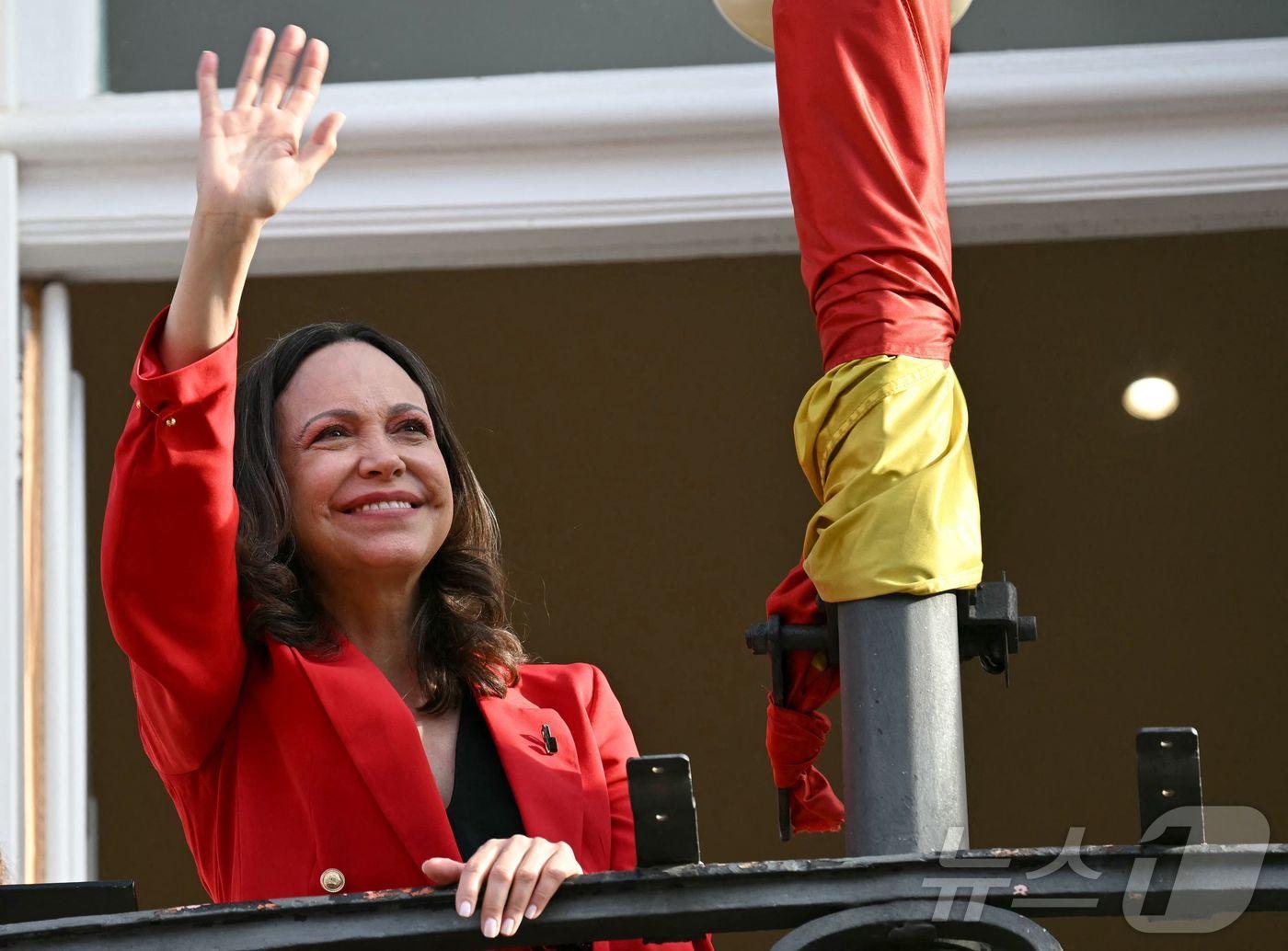 본문 이미지 - 베네수엘라 야당 지도자 마리아 코리나 마차도가 18일(현지시간) 마드리드 푸에르타 델솔에서 지지자들에게 손을 흔들고 있다. 2026.4.18 ⓒ AFP=뉴스1
