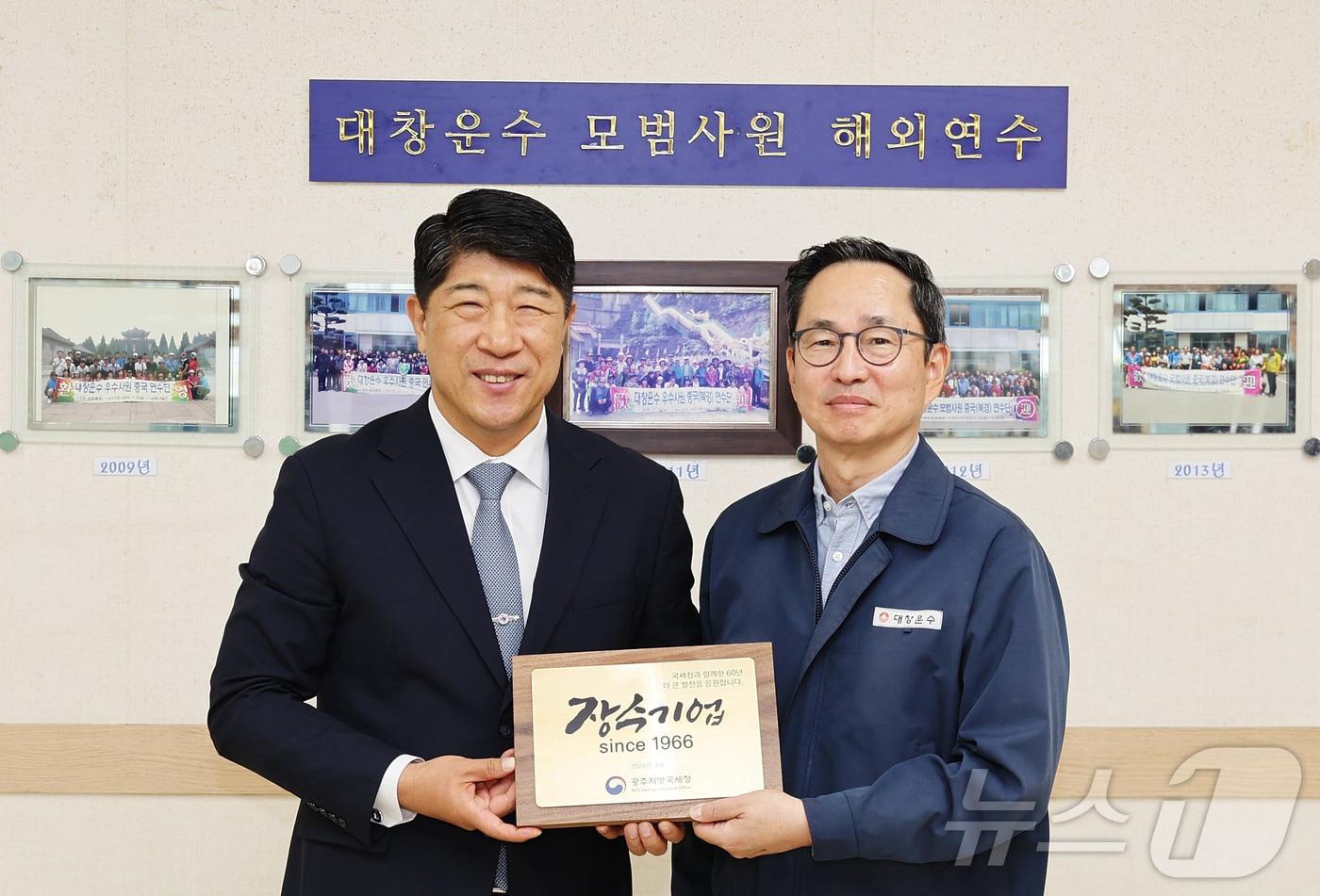 본문 이미지 - 김학선 광주지방국세청장(왼쪽)이 대창운수에 '60년 장수기업'을 기념하는 현판을 전달하고 있다.(광주국세청 제공, 재배포 및 DB 금지) /뉴스1