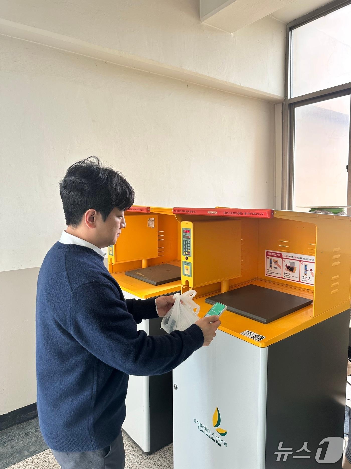 본문 이미지 - 스마트폰 앱을 활용해 음식물쓰레기 자동계량장비(RFID)를 이용하고 있는 모습.(용인시 제공)