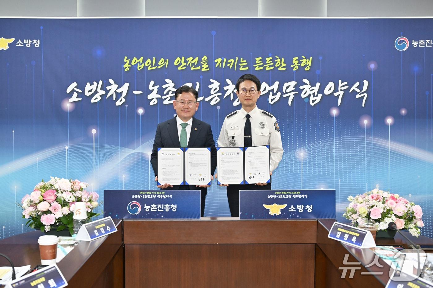 본문 이미지 - 김승룡 소방청장(오른쪽)과 이승돈 농촌진흥청장이 '농업 현장 안전 체계 구축 강화를 위한 업무협약'을 체결한 뒤 협약서를 들고 기념촬영을 하고 있다.(소방청 제공)