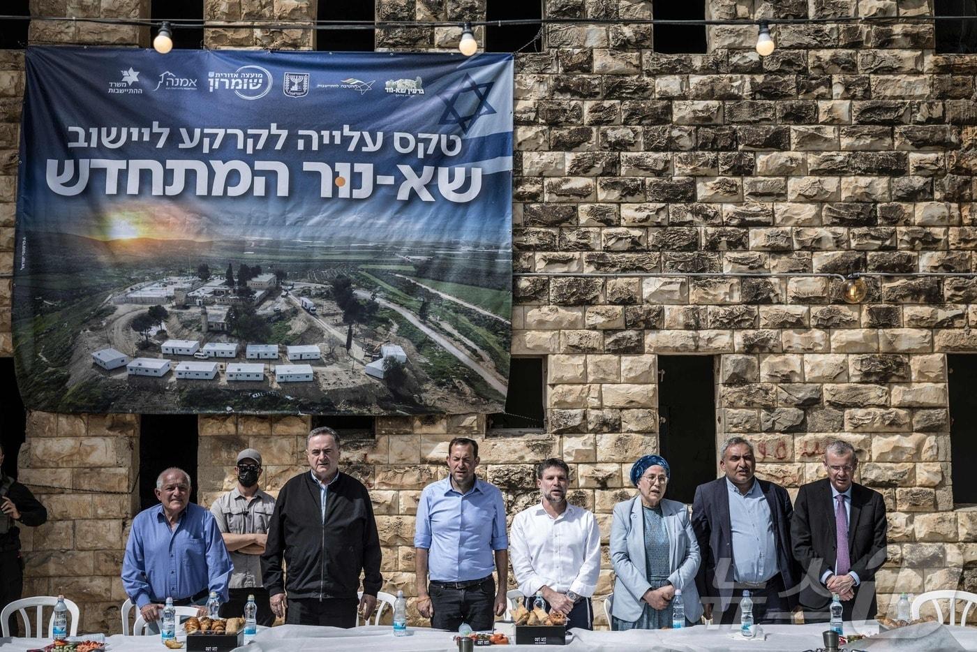 본문 이미지 - 19일(현지시간) 열린 팔레스타인 서안지구 사누르 정착촌 재정착 기념식에서 이스라엘 카츠 이스라엘 국방장관(왼쪽에서 세 번째), 요시 다간 쇼므론 지역협의회 의장(왼쪽에서 네 번째), 그리고 베잘렐 스모트리히 이스라엘 극우 재무장관(오른쪽에서 네 번째)이 국가 제창을 위해 서 있다. 2026.04.19. ⓒ AFP=뉴스1