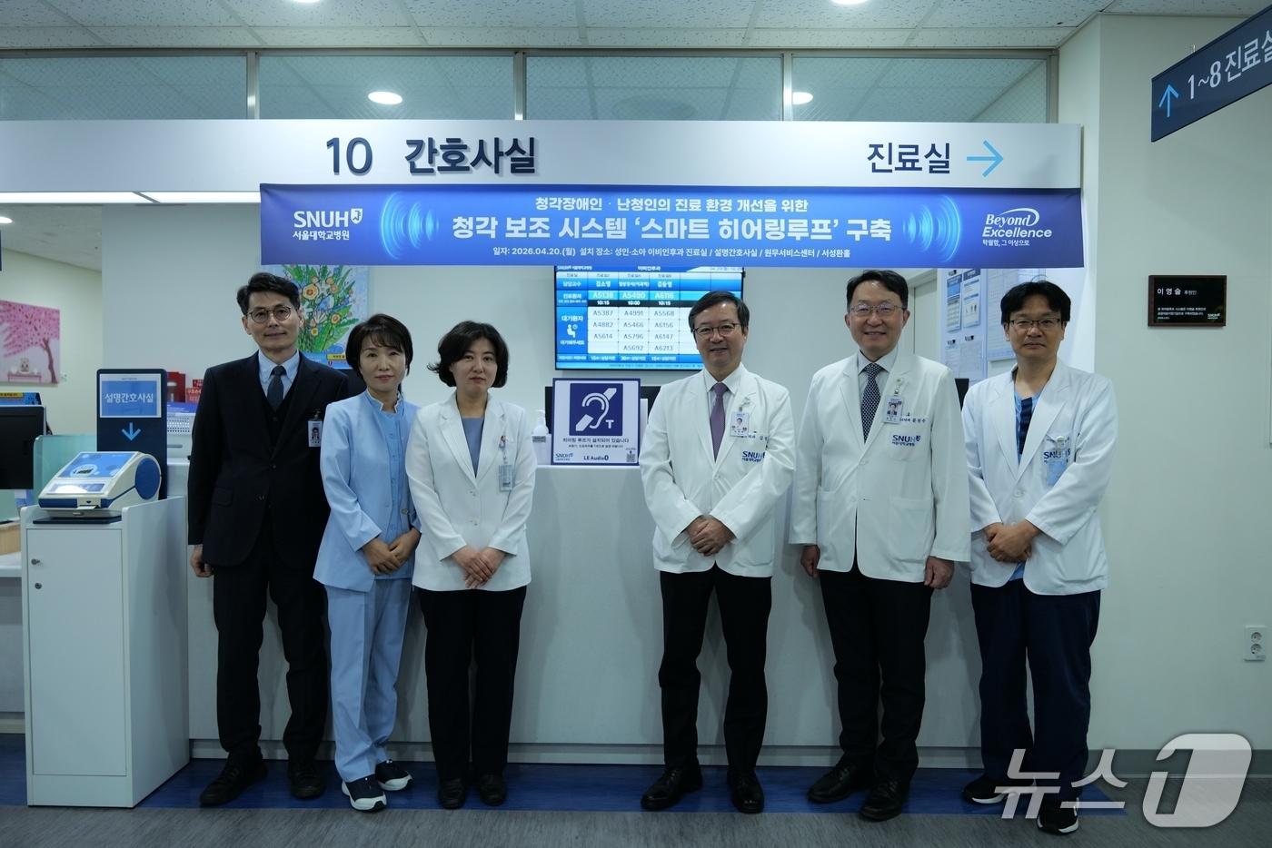 본문 이미지 - 성인이비인후과 설명간호사실 앞에 구축된 '스마트 히어링루프' 시스템. 왼쪽부터 구축 기념 행사에 참석한 김영태 서울대병원장(4번째), 문진수 서울대병원 공공부원장(5번째).(서울대병원 제공)