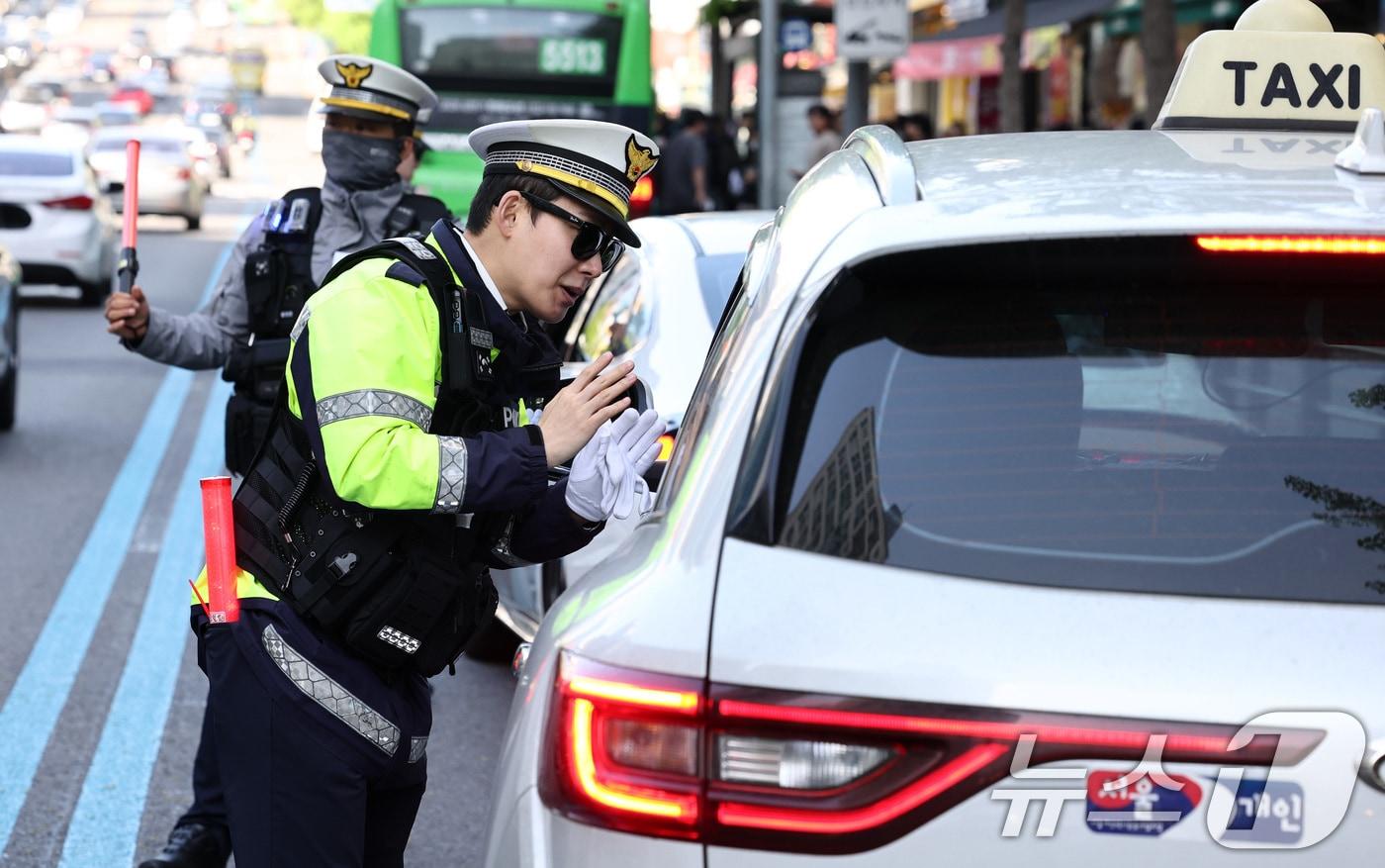본문 이미지 - 20일 서울 관악구 봉천로 사거리에서 교통안전계 경찰관들이 우회전 일시 정지 의무 위반 집중단속을 하고 있다. 현행 도로교통법에 따르면 우회전하려는 운전자는 전방 신호가 빨간불일 경우 반드시 일시 정지해야 하며, 우회전 후에도 보행자가 있거나 건너려 할 때는 멈춰야 한다. 경찰청은 오는 6월 19일까지 2달간 우회전 통행 방법 위반에 대한 집중 단속을 실시할 방침이다. 2026.4.20 ⓒ 뉴스1 최지환 기자