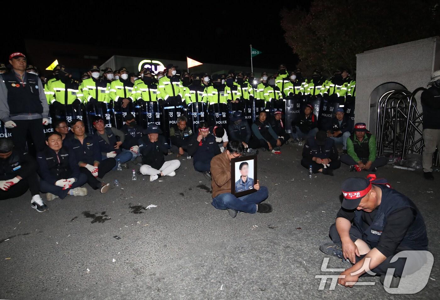 본문 이미지 - 20일 경남 진주시 정촌면 CU 진주물류센터 앞에서 화물연대 노조원이 집회 중 2.5톤 화물차에 치어 숨진 노조원의 영정을 들고 있다.  2026.4.20 ⓒ 뉴스1 윤일지 기자