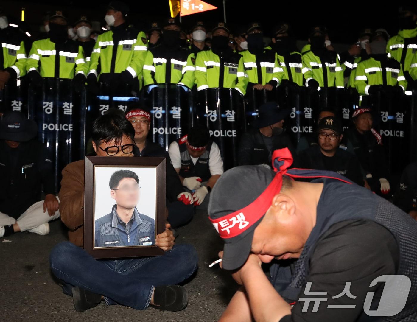 본문 이미지 - 20일 경남 진주시 정촌면 CU 진주물류센터 앞에서 화물연대 노조원이 집회 중 2.5톤 화물차에 치어 숨진 노조원의 영정을 들고 슬픔에 잠겨 있다. 이날 현장에서는 화물차와 집회 참가자 3명이 충돌해 1명이 숨지고 2명이 다치는 사고가 발생했다. 2026.4.20 ⓒ 뉴스1 윤일지 기자