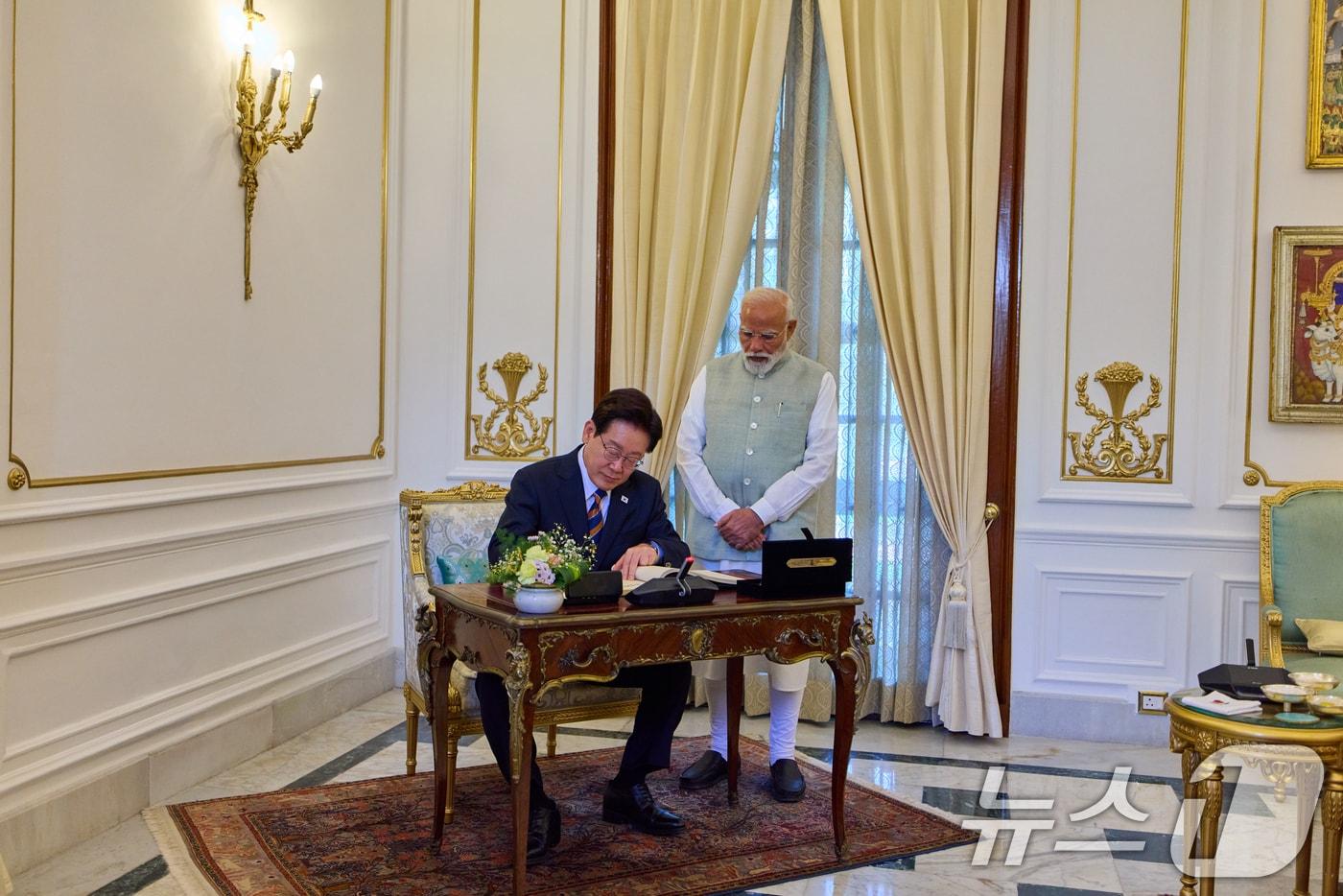 본문 이미지 - 인도를 국빈 방문 중인 이재명 대통령이 20일 뉴델리 영빈관에서 방명록을 작성하고 있다. 오른쪽은 나렌드라 모디 인도 총리. (공동취재) 2026.4.20 ⓒ 뉴스1 이재명 기자