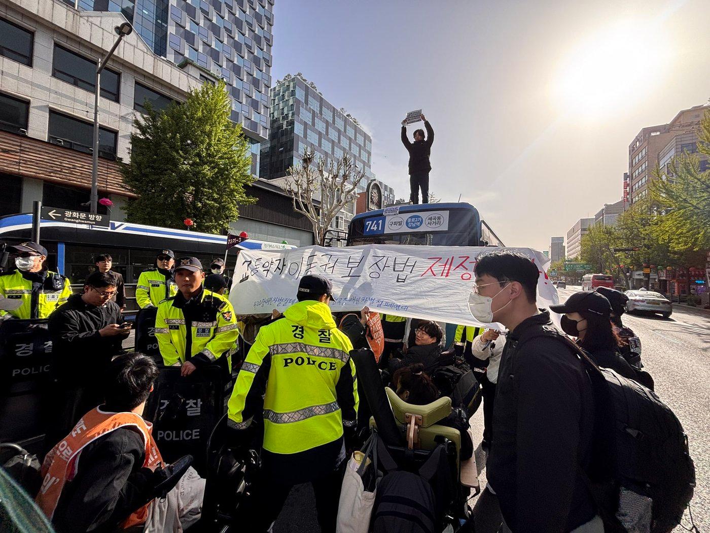 본문 이미지 - 전장연 소속 활동가들이 21일 오전 8시쯤부터 서울 종로구 종로2가 버스정류장 등에서 휠체어를 탄 채 시내버스를 저지하고 있는 모습.(전장연 제공)