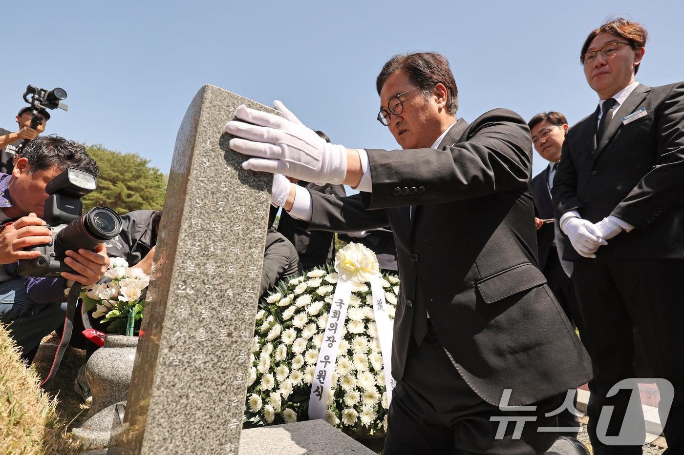 본문 이미지 - 우원식 국회의장이 21일 광주 북구 운정동 국립 5·18민주묘지에서 오월영령에 참배 후 윤상원 열사의 묘비를 정성스럽게 닦고 있다. 2026.4.21 ⓒ 뉴스1 박지현 기자