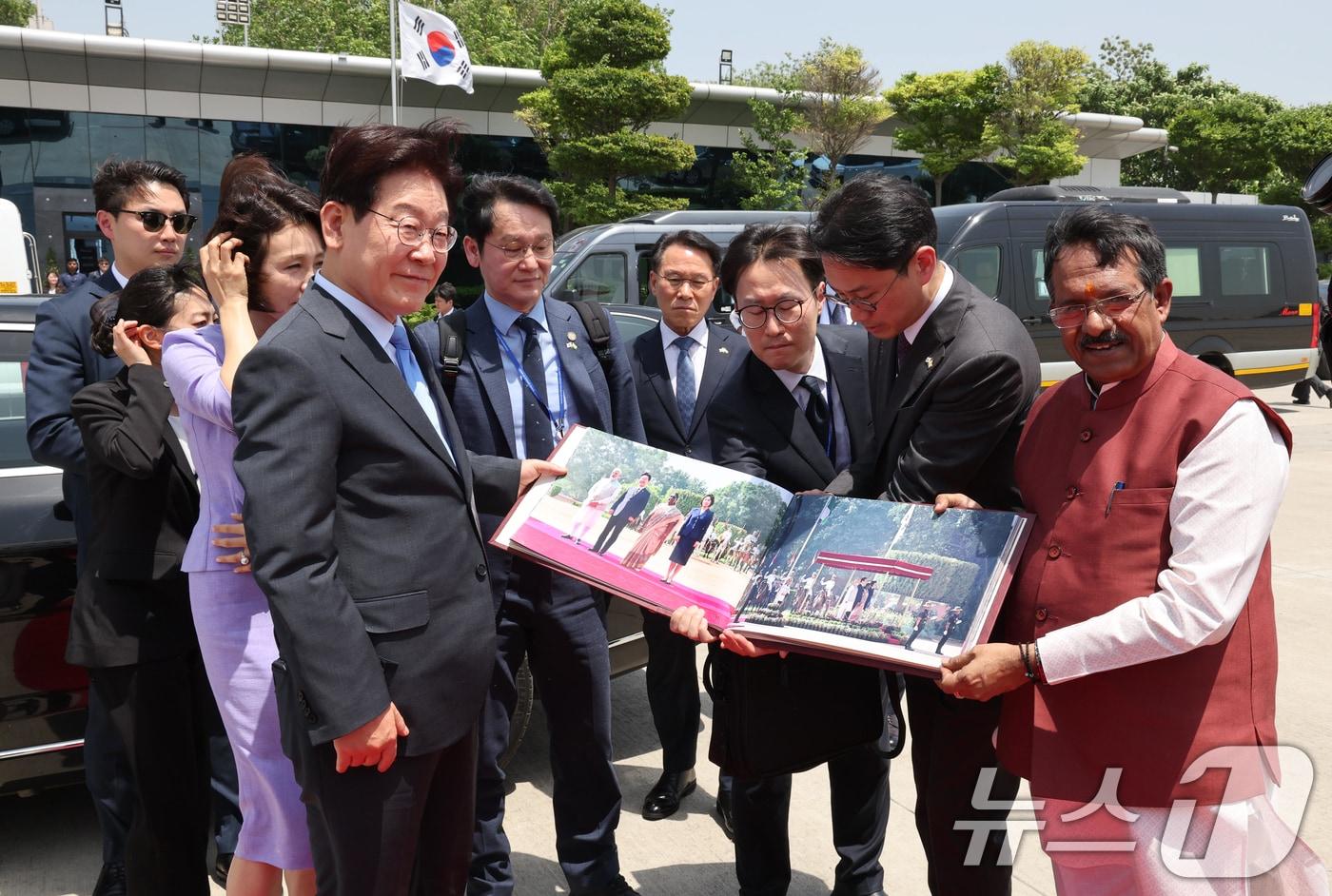 본문 이미지 - 인도 국빈 방문을 마친 이재명 대통령과 김혜경 여사가 21일(현지시간) 뉴델리 팔람 군비행장에서 베트남행 공군 1호기 탑승 전 사진첩을 선물 받고 있다. 2026.4.21 ⓒ 뉴스1 이재명 기자
