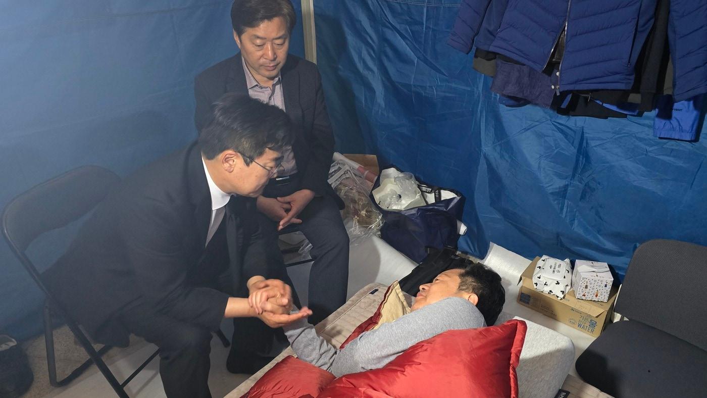 본문 이미지 - 박찬대 민주당 인천시장 후보(시계방향 왼쪽)과 황명선 최고위원(오른쪽)이 침상에 누운 안호영 의원에게 단식 중단을 요청하고 있다. 2026.04.21 ⓒ 뉴스1 이승환 기자 