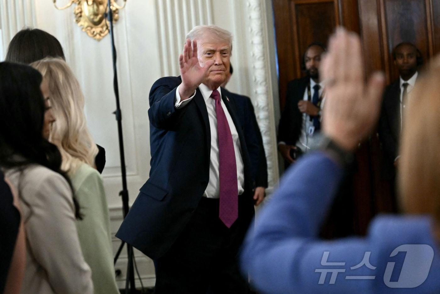 본문 이미지 - 도널드 트럼프 미국 대통령이 21일(현지시간0 백악관에서 열린 NCAA 대학 국가 챔피언 기념 행사에서 질문을 하려는 기자를 향해 손을 흔들고 있다. 2026.04.21 ⓒ AFP=뉴스1