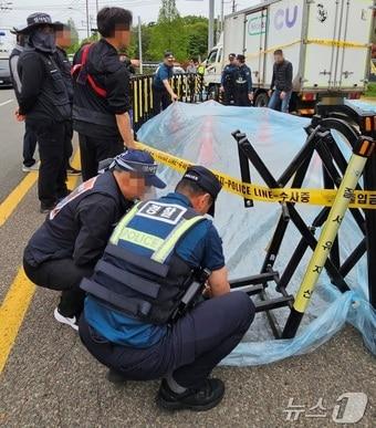 본문 이미지 - 22일 경남 진주시 정촌면 CU 진주물류센터 앞 민주노총 화물연대 조합원이 사망한 사고 현장 보존을 위해 조합원과 경찰이 방수포 작업을 하고 있다. 2026.4.22 ⓒ 뉴스1 한송학 기자