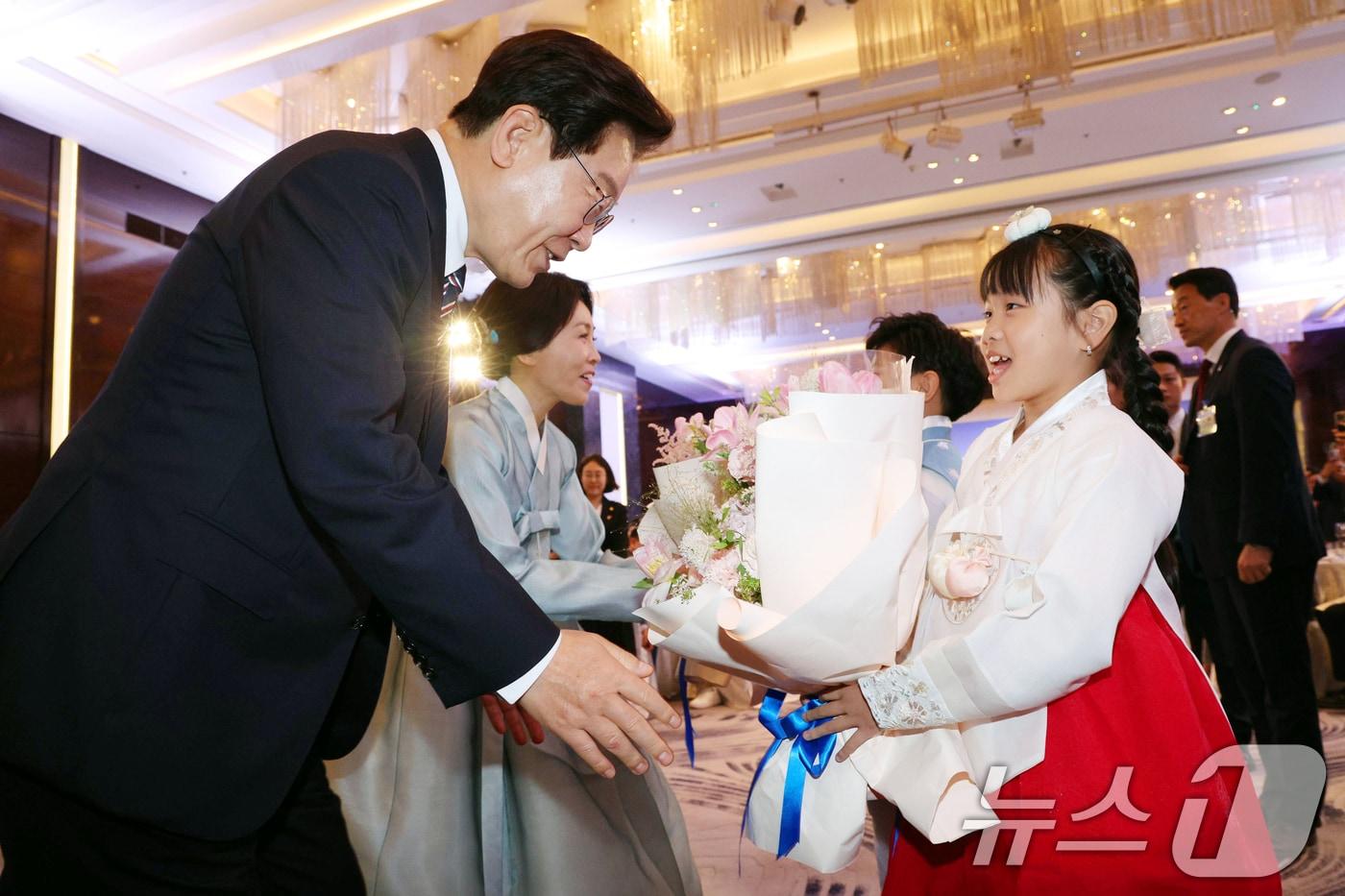 본문 이미지 - 베트남을 국빈 방문 중인 이재명 대통령과 김혜경 여사가 22일(현지시간) 하노이의 한 호텔에서 열린 동포 오찬 간담회에서 화동에게 꽃다발을 받고 있다. 2026.4.22 ⓒ 뉴스1 이재명 기자