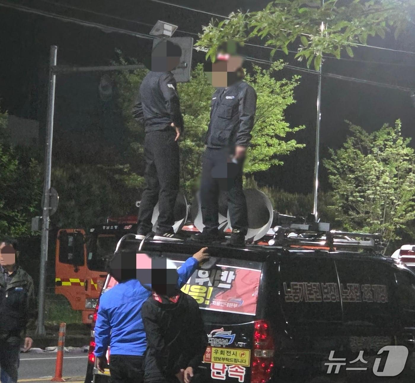 본문 이미지 - 지난 19일 진주시 정촌면 예하리 CU 진주물류센터 앞 화물연대 집회 현장에 세워진 화물연대 승합차 위에서 조합원 A 씨가 흉기를 들고 다른 조합원과 대치하고 있다.(독자제공. 재판매 및 DB금지)