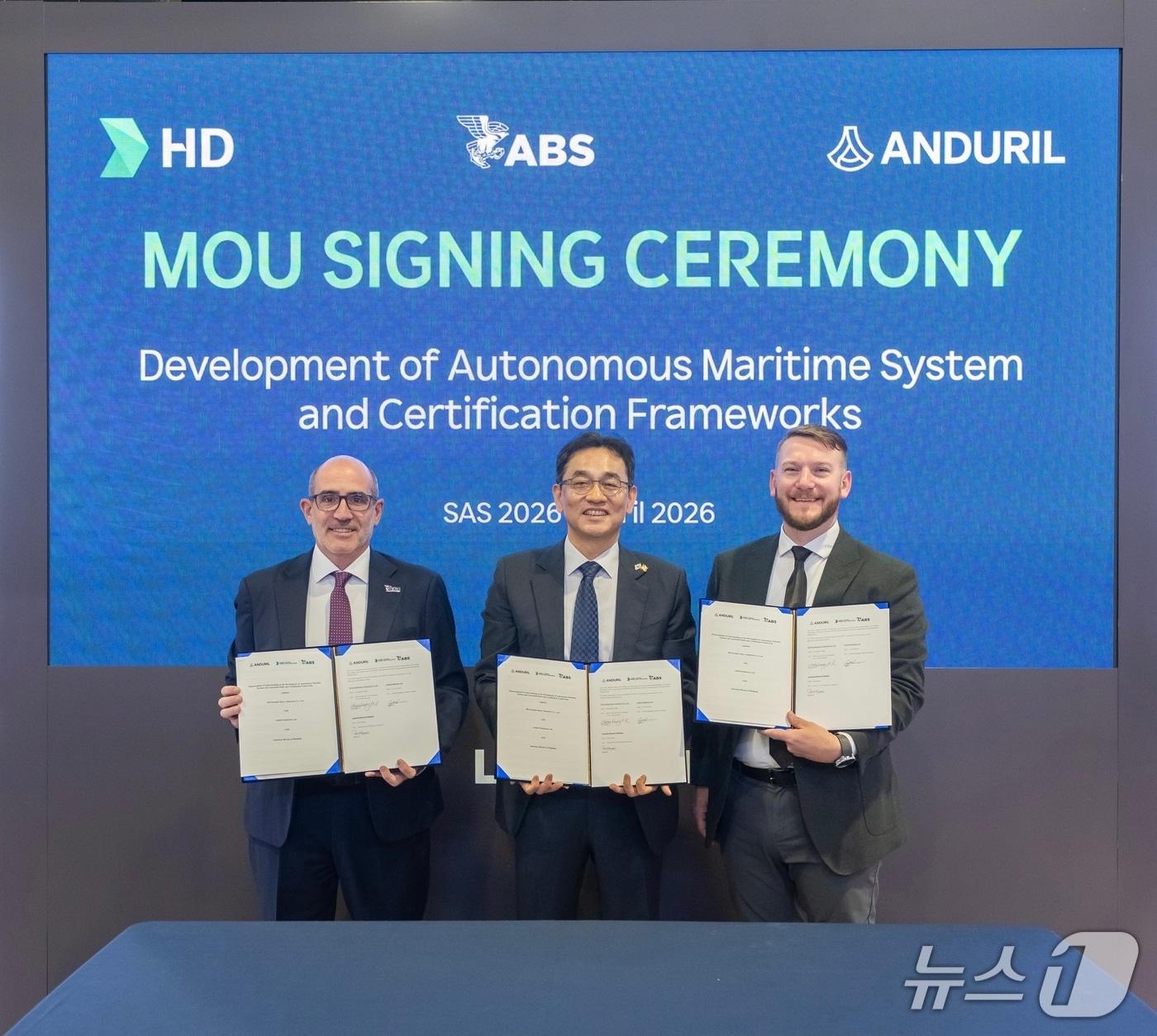 본문 이미지 - 미국 워싱턴DC에서 22일(현지시각) 진행된 '해양항공우주 전시회'(Sea Air Space 2026·SAS 2026) HD현대 전시관에서 (오른쪽부터) 코리 에먼스 안두릴 수상함사업 총괄본부장, 장광필 HD한국조선해양 미래기술연구원장 부사장, 폴 카람 미국선급협회(ABS) 운영부문 부사장 등이 '자율 해양 시스템 및 관련 규정·인증 프레임워크 개발에 관한 3자 업무협약(MOU)'를 맺은 뒤 기념 사진을 촬영한 모습(HD현대 제공). 2026.4.22.