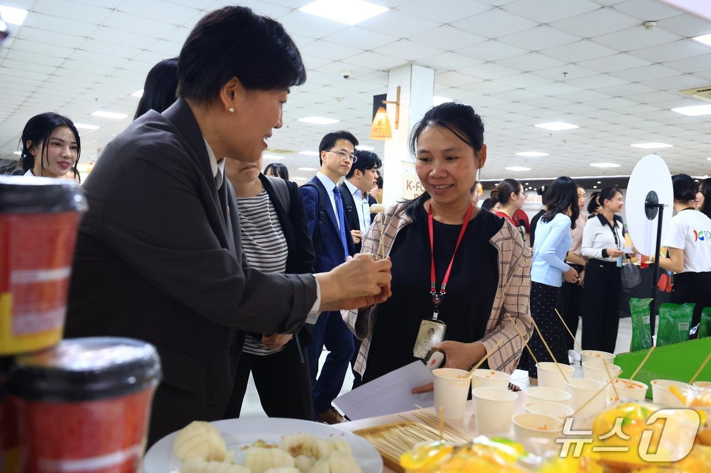 본문 이미지 - 농림축산식품부는 22~23일 베트남을 방문 중인 송미령 장관이 K-외식 프랜차이즈와 급식 채널을 활용한 K-푸드 수출 확대에 나섰다고 밝혔다.  송 장관이 현지인에게 K-푸드 시식을 권하고 있다. (농식품부 제공) /2026.4.23/