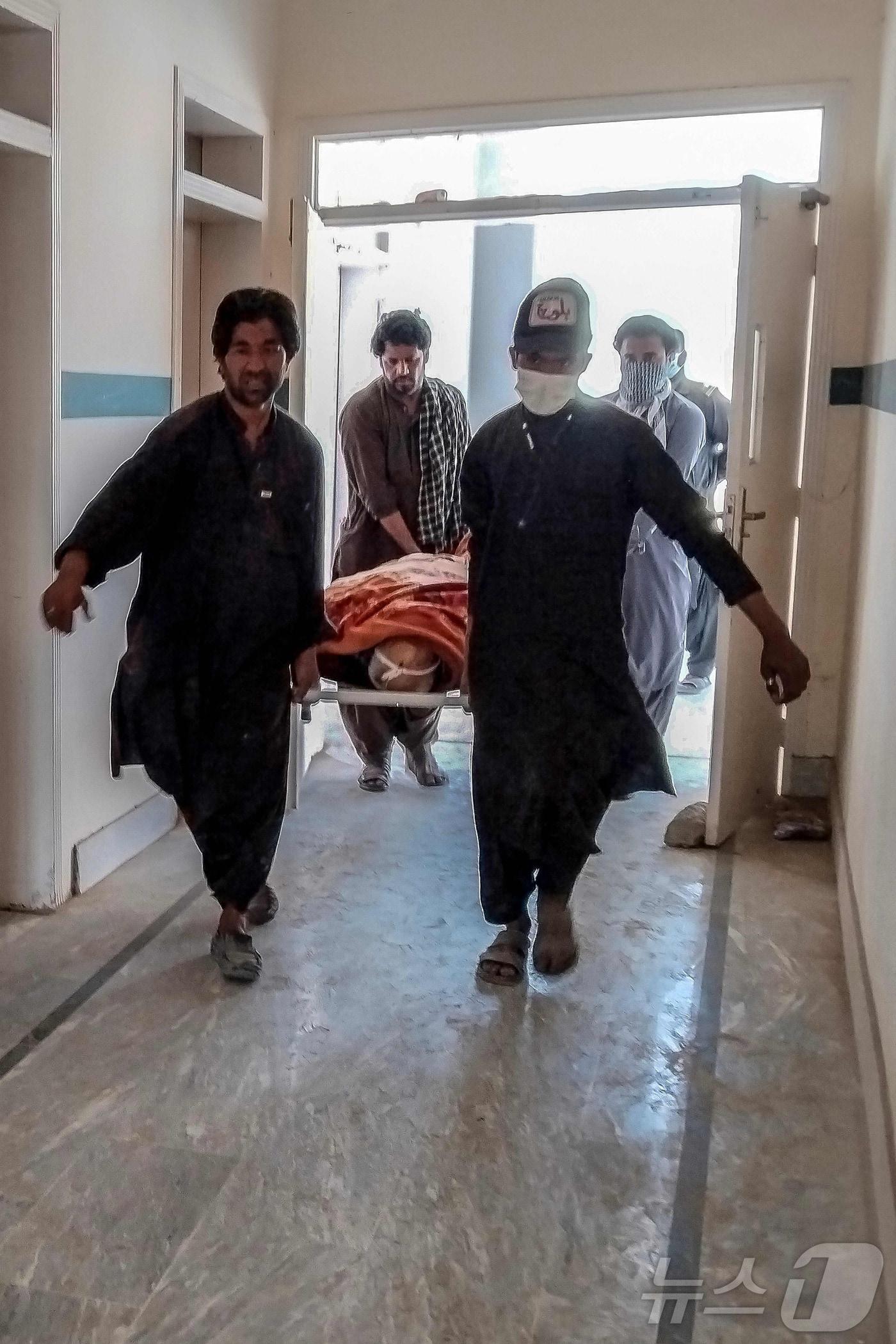 본문 이미지 - 23일(현지시간) 파키스탄 발루치스탄주에서 발생한 무장단체 공격 이후 자원봉사자들이 병원에서 광산 노동자의 시신을 옮기고 있다. 2026.04.23. ⓒ AFP=뉴스1