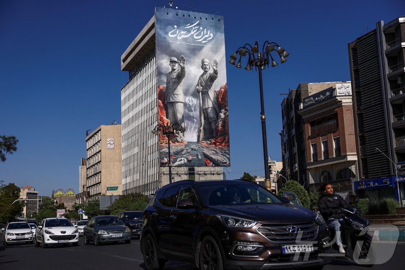 본문 이미지 - 22일(현지시간) 이란 수도 테헤란의 한 건물에 호르무즈 해협 관련 광고판이 설치돼 있다. 2026.4.22. ⓒ 로이터=뉴스1