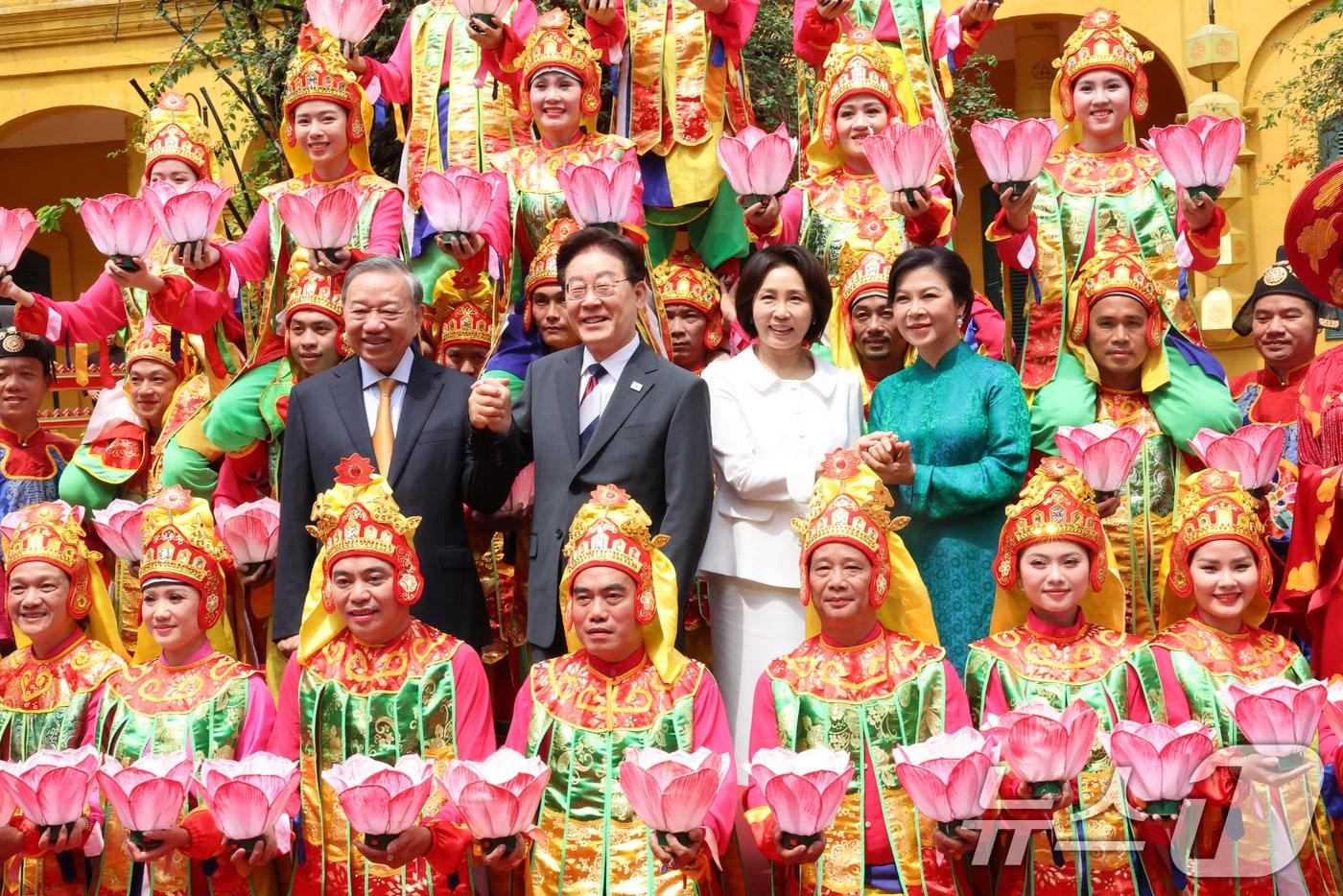 본문 이미지 - 이재명 대통령, 김혜경 여사와 또 럼 베트남 당 서기장 겸 국가주석, 응오 프엉 리 여사가 24일(현지시간) 친교일정으로 베트남 탕롱 황성를 방문해 공연단과 기념촬영을 하고 있다. 2026.4.24 ⓒ 뉴스1 이재명 기자