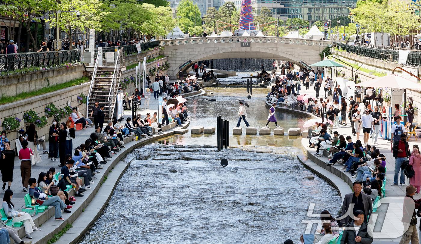 본문 이미지 - 낮 최고기온이 26도까지 오르며 초여름 날씨를 보인 24일 오후 서울 청계천을 찾은 시민들이 더위를 식히고 있다. 2026.4.24 ⓒ 뉴스1 조연우 인턴기자