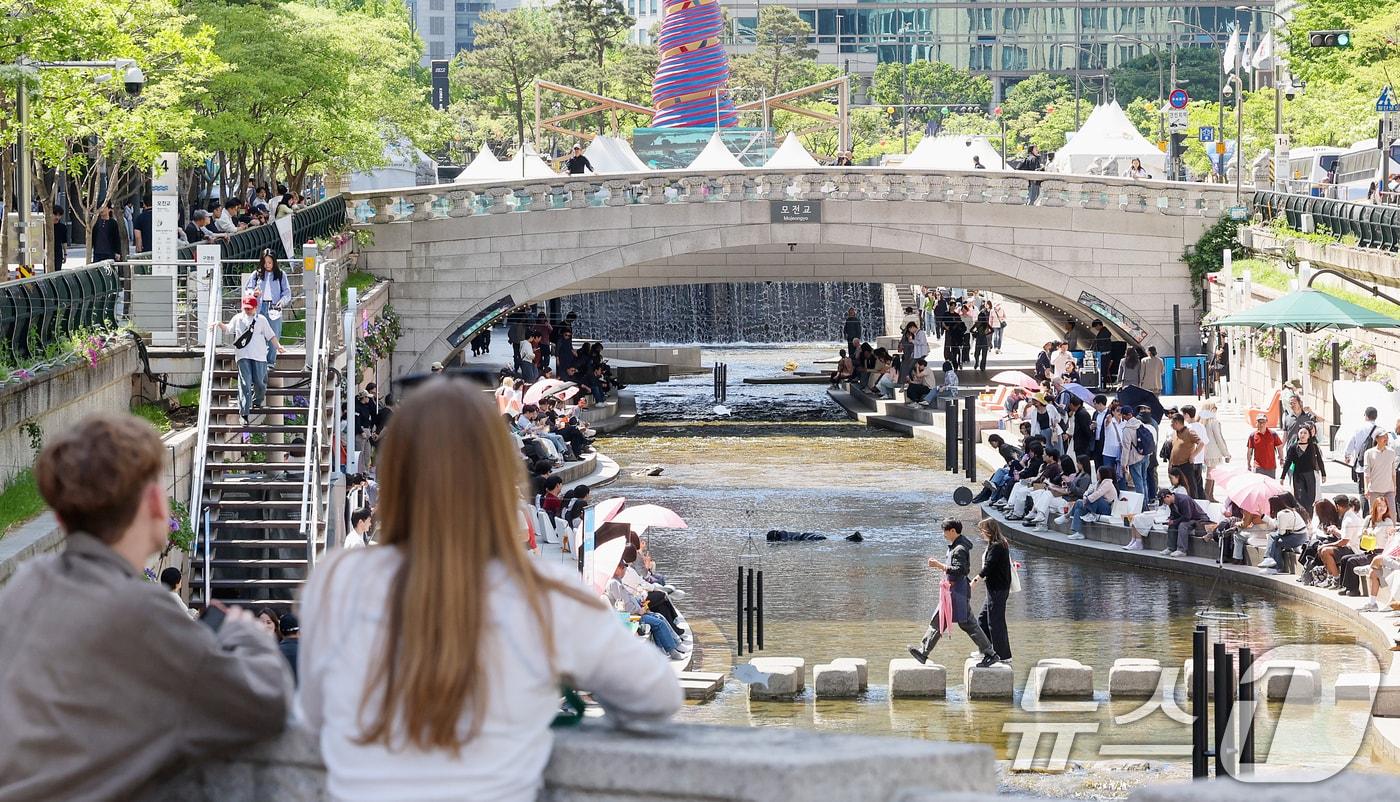 본문 이미지 - 낮 최고기온이 26도까지 오르며 초여름 날씨를 보인 24일 오후 서울 청계천을 찾은 시민들이 더위를 식히고 있다. 2026.4.24 ⓒ 뉴스1 조연우 인턴기자