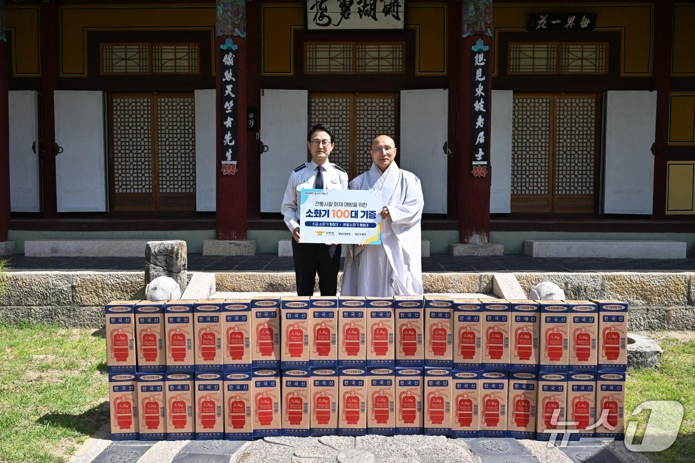 본문 이미지 - 24일 경남 양산시 통도사를 방문한 김승룡 소방청장(왼쪽)이 현덕 주지스님과 함께 사찰 화재 예방을 위한 소화기 100대 기증 피켓을 들고 기념촬영을 하고 있다.(소방청 제공)