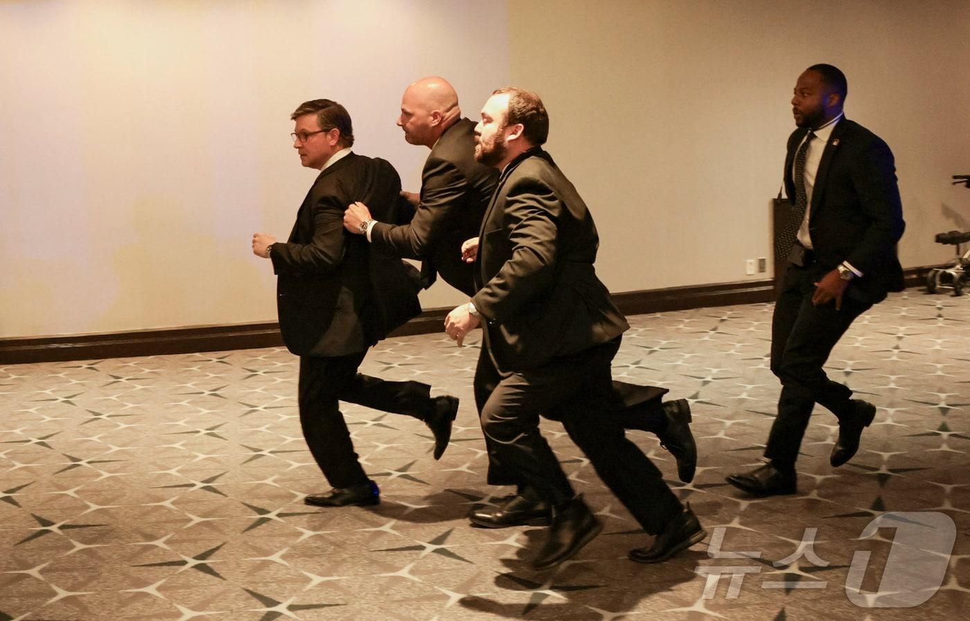 본문 이미지 - 25일(현지시간) 미국 워싱턴DC에서 열린 백악관 출입기자단 만찬 중 행사장 인근에서 총성이 들리자 백악관 경호원들이 마이크 존슨 하원의장을 대피시키고 있다. 2026.04.25 ⓒ 로이터=뉴스1