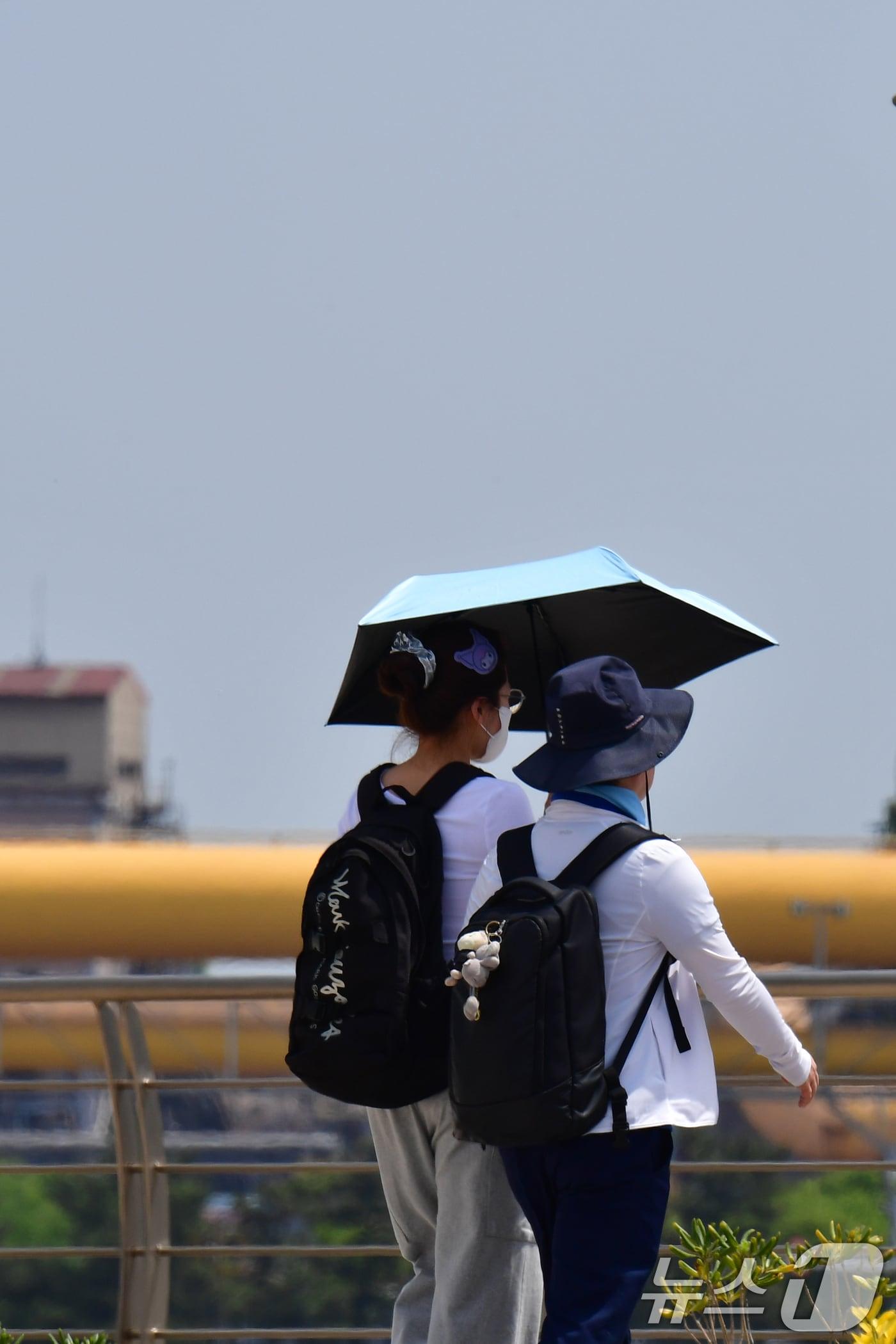 본문 이미지 - 지난 26일 경북 포항시 송도해수욕장 해안길에서 양산을 쓴 관광객들이 걸어가고 있다. 2026.4.26 ⓒ 뉴스1 최창호 기자
