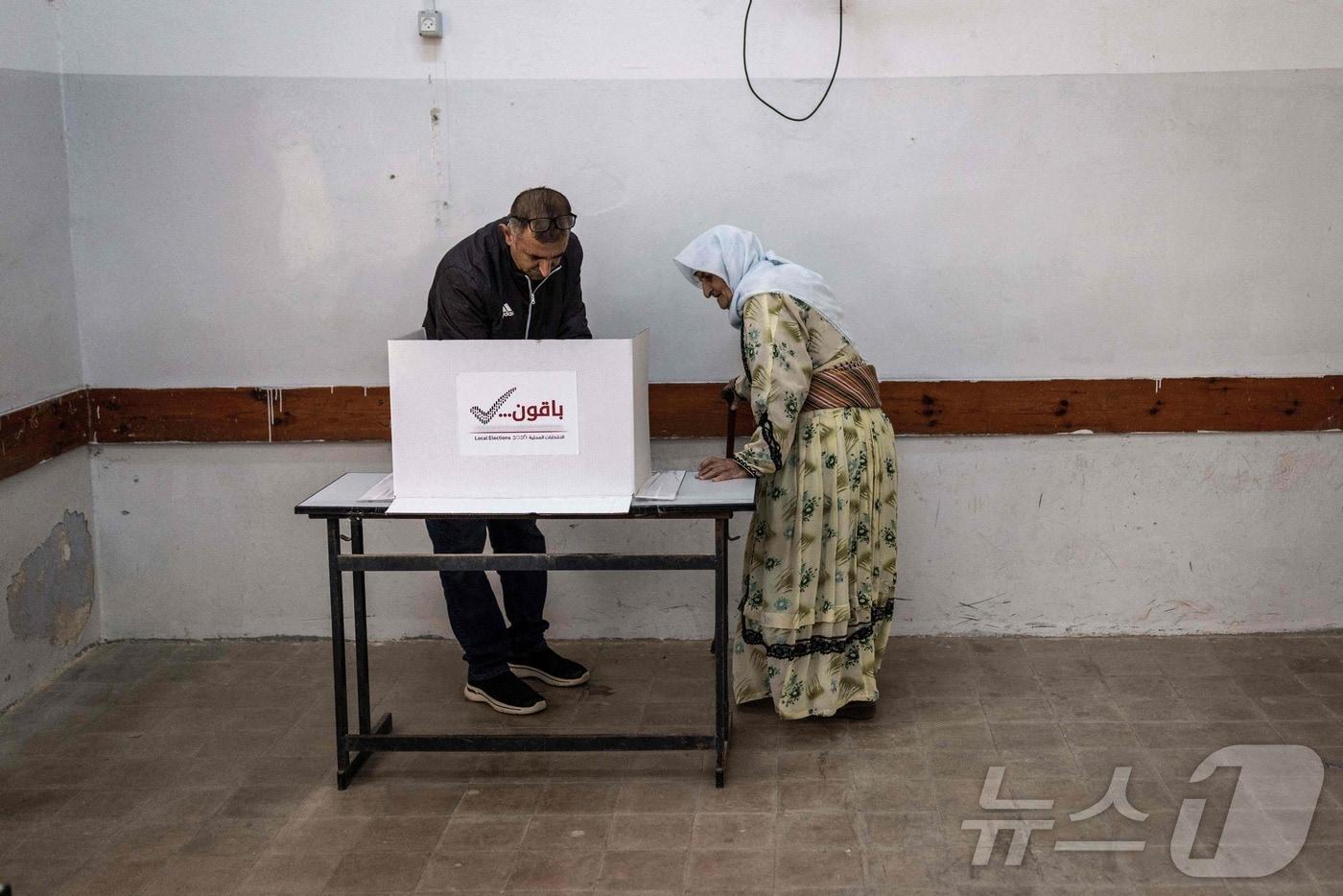 본문 이미지 - 25일(현지시간) 팔레스타인 요르단강 서안지구 제닌 남쪽 카바티야 마을에서 열린 지방선거에서 한 팔레스타인 고령 여성이 투표소에서 투표용지를 표시하고 있다. 이날 서안지구와 가자지구 중앙 일부 지역에서 전쟁 이후 처음으로 지방선거가 실시됐다. 2026.04.25. ⓒ AFP=뉴스1