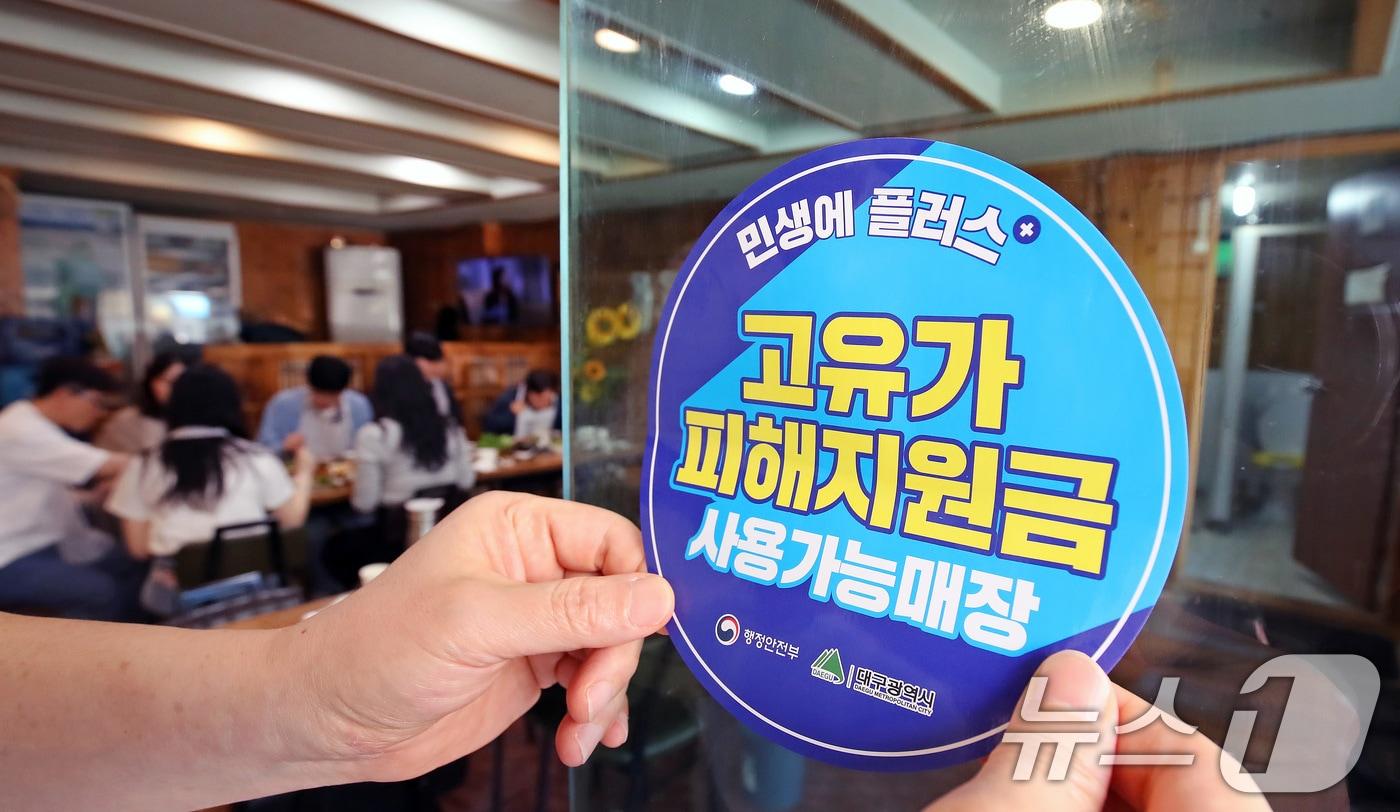 본문 이미지 - 고유가 피해지원금 1차 지급이 시작된 지난 4월27일 대구 수성구의 한 음식점에서 상인이 고유가 피해지원금 사용 가능 매장을 알리는 스티커를 붙이고 있다. 2026.4.27 ⓒ 뉴스1 공정식 기자