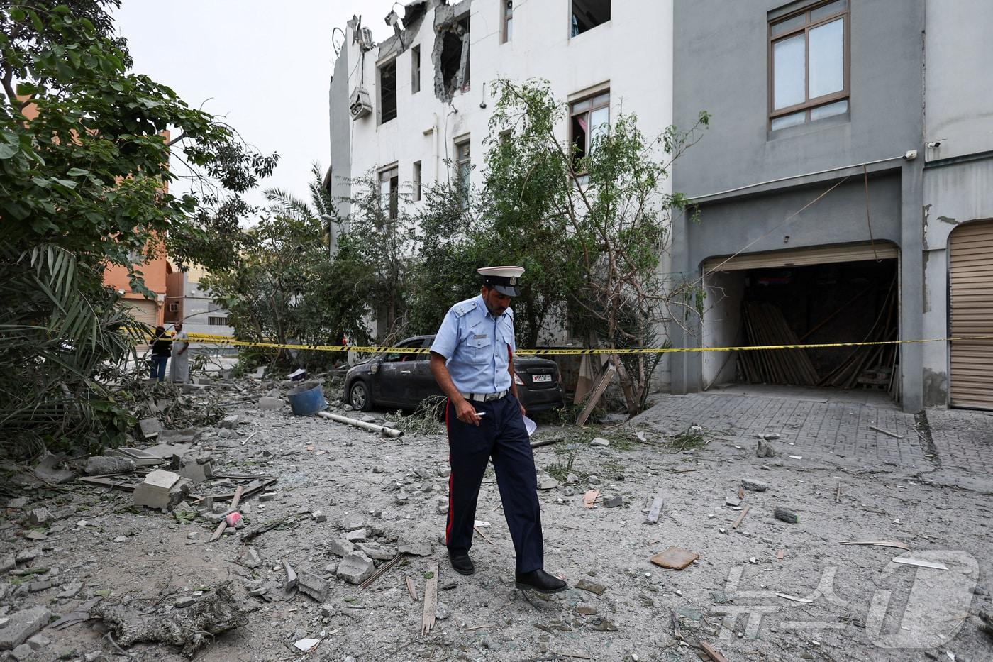 본문 이미지 - 지난 4일(현지시간) 바레인 시트라에서 한 경찰관이 이란 무인기(드론) 파편이 떨어진 현장을 살피고 있다. 2026.04.04. ⓒ 로이터=뉴스1