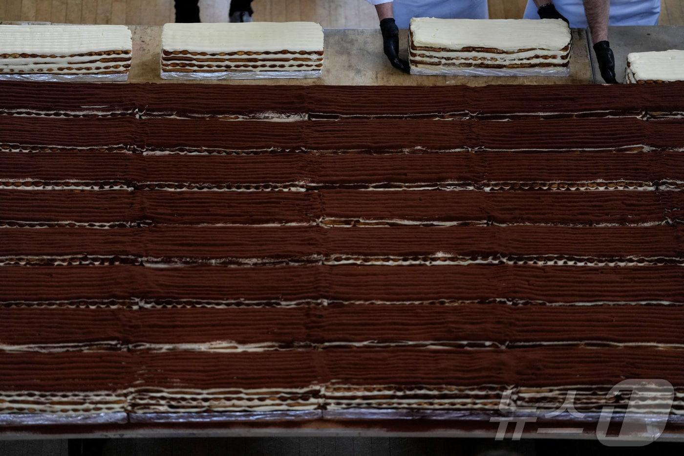 본문 이미지 - 26일(현지시간) 영국 런던 첼시 타운홀에서 셰프들과 자원봉사자들이 세계 최장 티라미수 기네스 기록을 경신하는 모습.2026.04.26.ⓒ 로이터=뉴스1