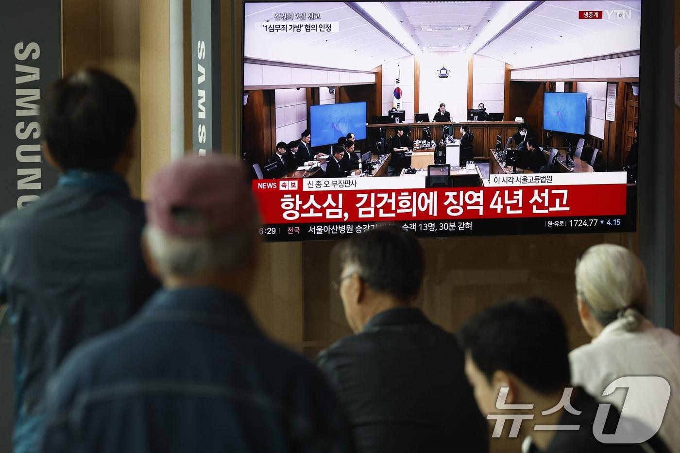 본문 이미지 - 28일 오후 서울시 용산구 한강대로 서울역 대합실에서 시민들이 자본시장과 금융투자업에 관한 법률 위반, 정치자금법 위반, 특정범죄 가중처벌 등에 관한 법률 위반(알선수재) 혐의를 받는 김건희 여사의 항소심 선고공판 생중계를 지켜보고 있다. 이날 김건희 여사는 징역 4년·벌금 5000만원을 선고 받았다. 2026.4.28 ⓒ 뉴스1 박정호 기자