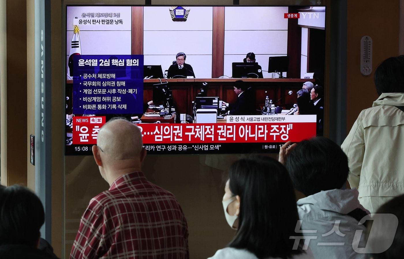 본문 이미지 - 29일 오후 서울시 용산구 한강대로 서울역 대합실에서 시민들이 특수공무집행방해, 직권남용 권리행사방해, 허위 공문서 작성 등의 혐의를 받는 윤석열 전 대통령의 항소심 선고 공판 생중계를 지켜보고 있다. 2026.4.29 ⓒ 뉴스1 김진환 기자