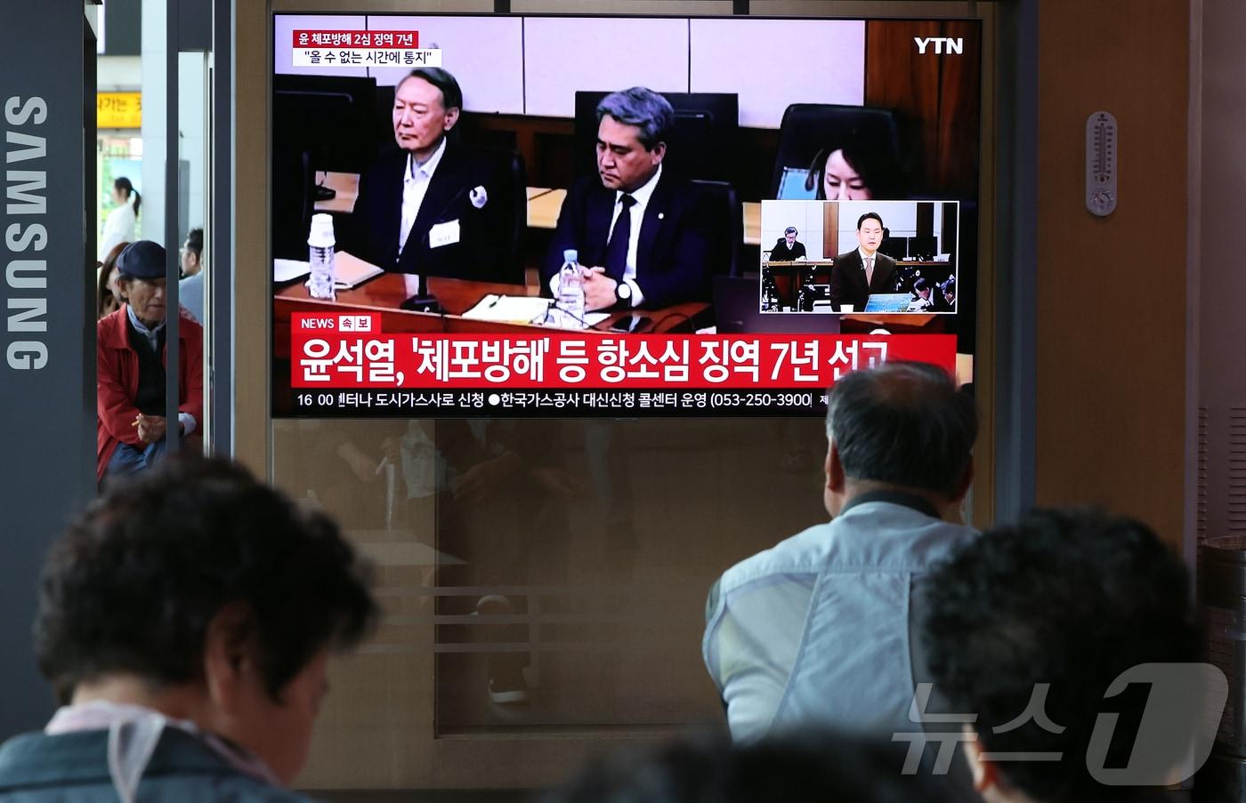 본문 이미지 - 29일 오후 서울시 용산구 한강대로 서울역 대합실에서 시민들이 특수공무집행방해, 직권남용 권리행사방해, 허위 공문서 작성 등의 혐의를 받는 윤석열 전 대통령의 항소심 선고 공판 생중계를 지켜보고 있다. 윤 전 대통령은 지난 1심 징역 5년 보다 2년 높은 징역 7년형을 선고 받았다. 2026.4.29 ⓒ 뉴스1 김진환 기자