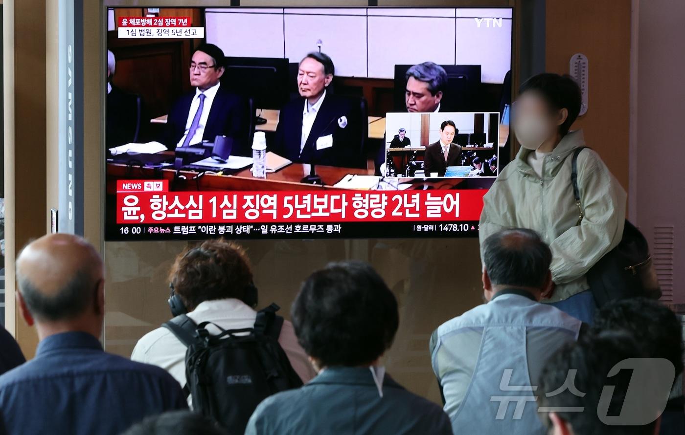 본문 이미지 - 29일 오후 서울시 용산구 한강대로 서울역 대합실에서 시민들이 특수공무집행방해, 직권남용 권리행사방해, 허위 공문서 작성 등의 혐의를 받는 윤석열 전 대통령의 항소심 선고 공판 생중계를 지켜보고 있다. 윤 전 대통령은 지난 1심 징역 5년 보다 2년 높은 징역 7년형을 선고 받았다. 2026.4.29 ⓒ 뉴스1 김진환 기자