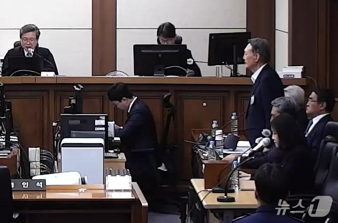 본문 이미지 - 특수공무집행방해·직권남용 권리행사방해 등의 혐의를 받는 윤석열 전 대통령이 29일 서울 서초구 서울고등법원에서 열린 항소심 선고공판에서 자리에서 일어나 주문을 듣고 있다. (서울고등법원 제공 영상 캡쳐. 재판매 및 DB 금지) 2026.4.29 ⓒ 뉴스1 오대일 기자