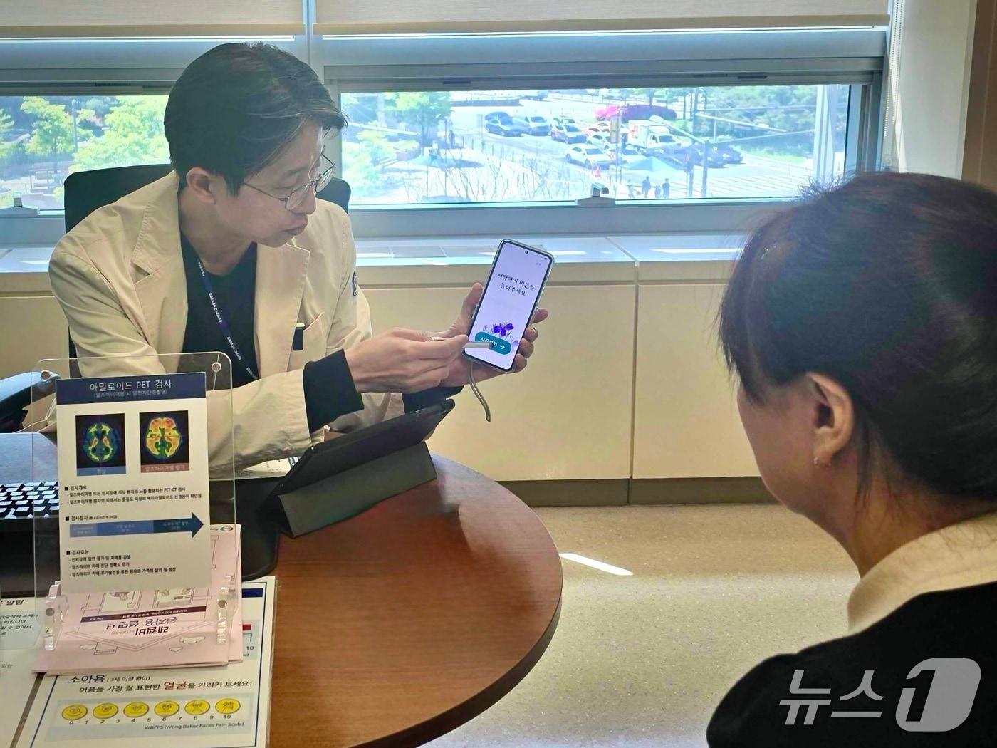 본문 이미지 - 강동우 가톨릭대 서울성모병원 정신건강의학과 교수가 경도인지장애 환자에게 디지털치료기기 '코그테라'를 활용한 인지치료 프로그램을 설명하고 있다.(이모코그 제공)