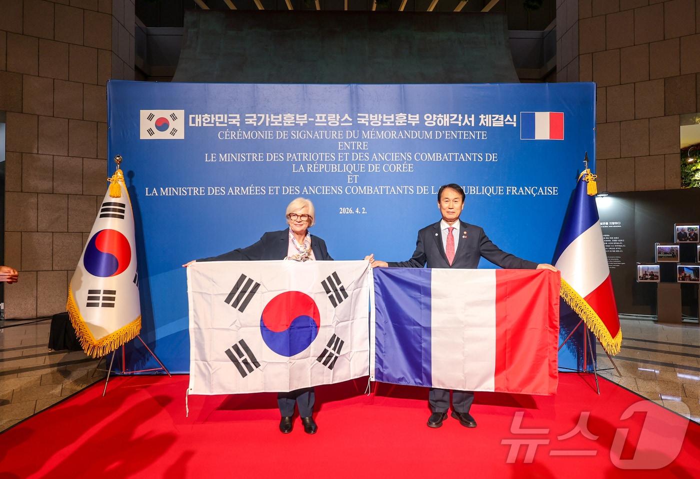 본문 이미지 - 권오을 국가보훈부 장관이 2일 오후 서울시 용산구 전쟁기념관에서 열린 대한민국 국가보훈부-프랑스 국방보훈부 양해각서 체결식에 참석해 카트린 보트랭 프랑스 국방보훈부 장관과 함께 협약서에 서명 후 양국 국기를 들고 기념촬영을 하고 있다. 2026.4.3 ⓒ 뉴스1