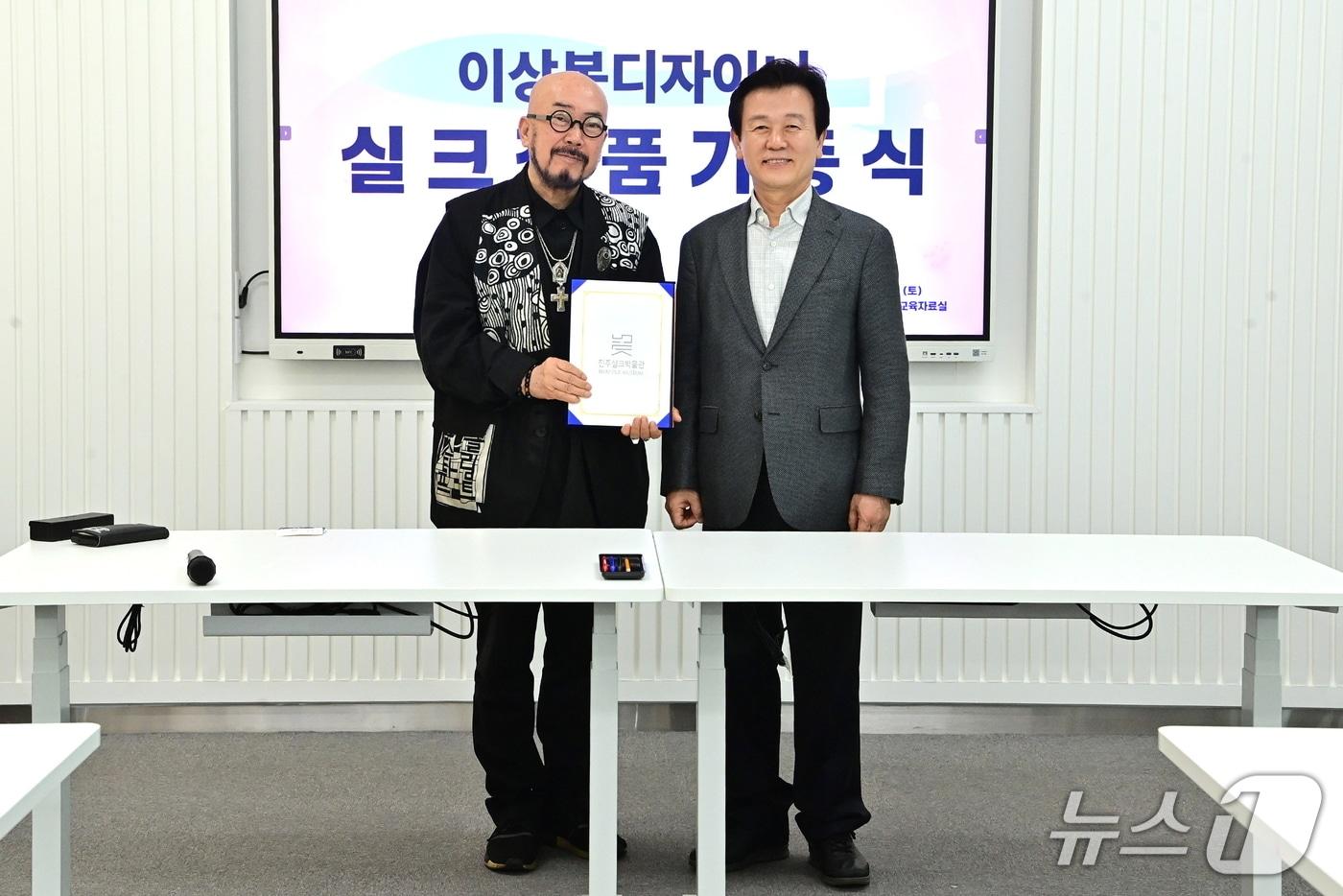 본문 이미지 - 조규일 진주시장(오른쪽)이 지난 4일 진주실크박물관에서 이상봉 패션 디자이너(왼쪽)의 실크 작품을 기증받고 있다(진주시 제공. 재판매 및 DB금지).