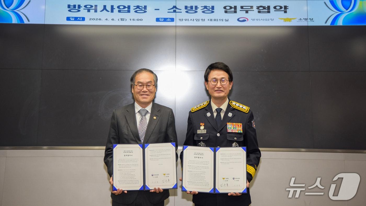 본문 이미지 - 김승룡 소방청장(오른쪽)과 이용철 방위사업청장이 6일 오후 정부과천청사에서 국가 재난 대응 역량 강화를 위한 업무협약을 체결한 뒤 협약서를 들어 보이며 기념촬영을 하고 있다.(소방청 제공)