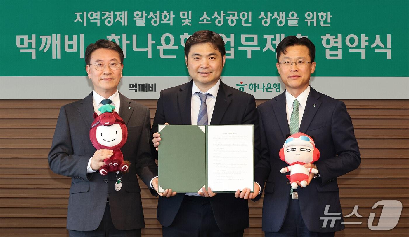 본문 이미지 - 지난 6일 서울시 중구 을지로 본점에서 열린 협약식에 참석한 서유석 하나은행 기업그룹 부행장(사진 오른쪽)과 김영호 하나은행 리테일그룹장(사진 왼쪽)이 김주형 먹깨비 대표(사진 가운데)와 함께 협약서를 들고 기념 촬영을 하고 있다. 2026.04.06 / 사진제공=하나은행